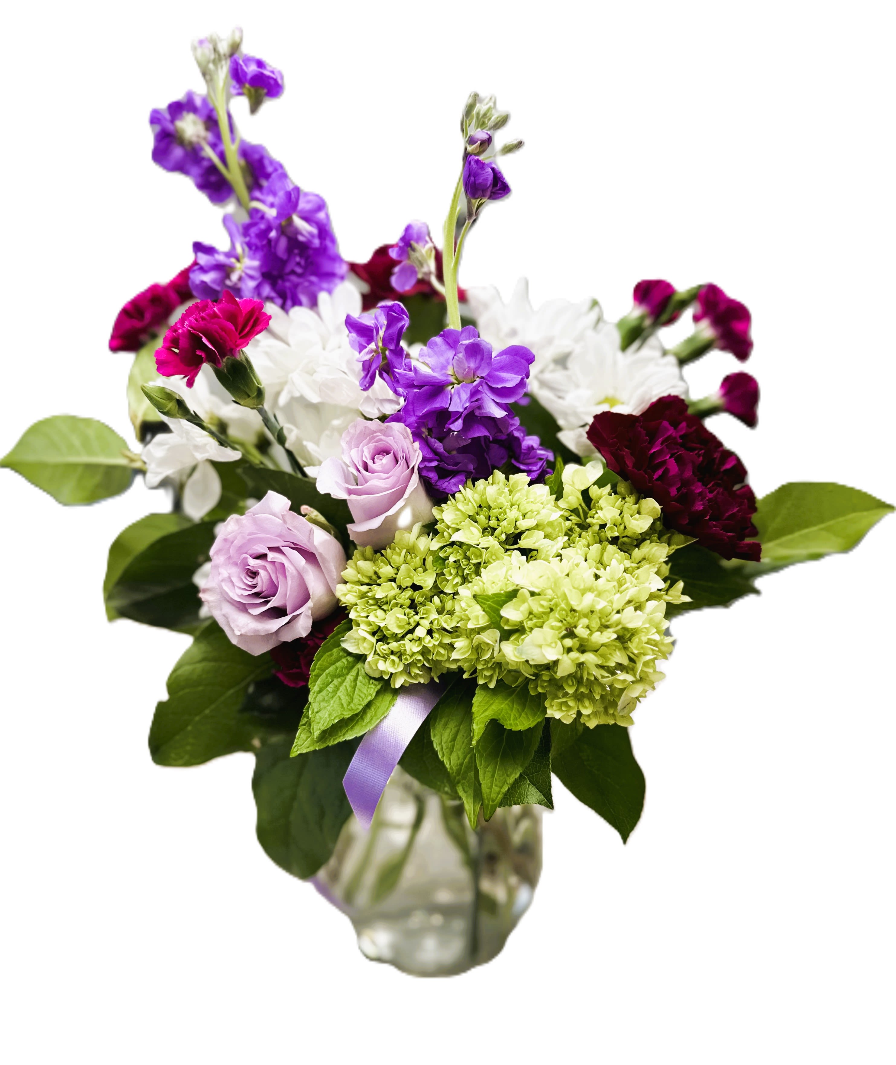 Mixed bouquet of purple, white, and green flowers in a glass vase