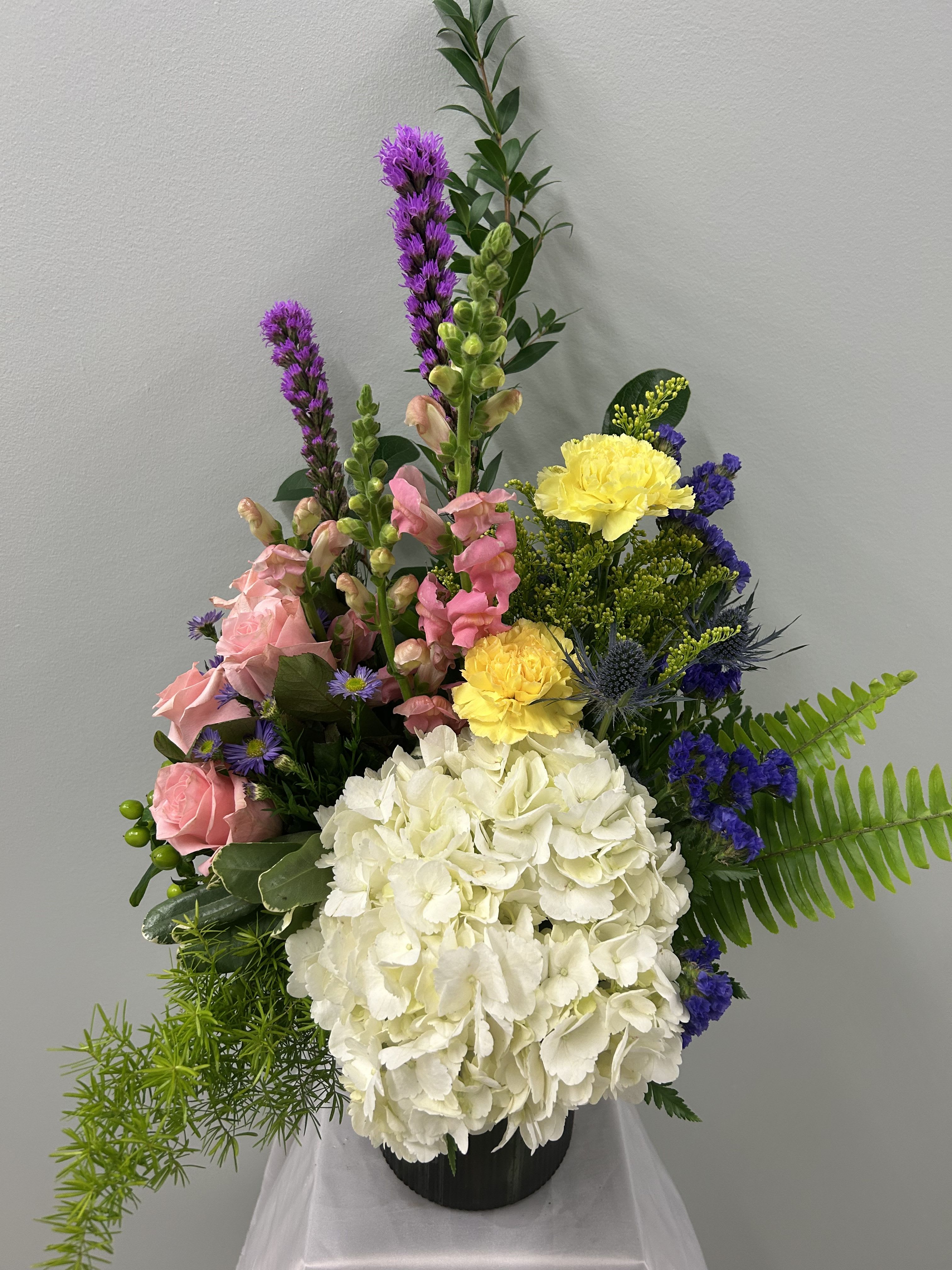 Garden of Eden - Cylinder vase featuring groupings of roses, hydrangea, snap dragons, carnations and other seasonal blooms