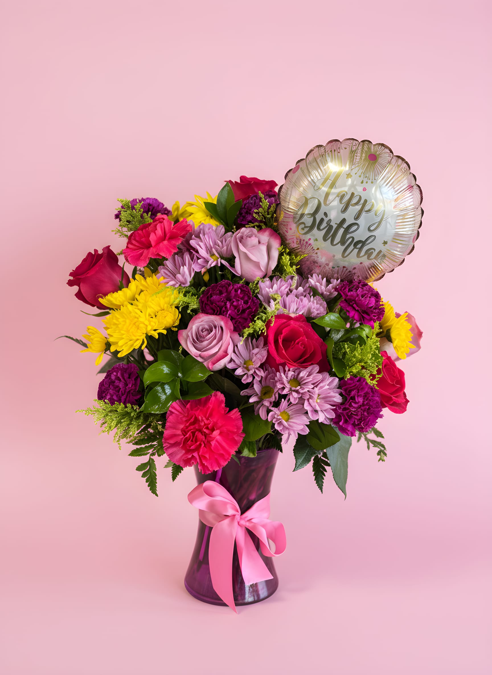 Birthday Bliss - A bright cluster of pink roses and hot pink carnations makes an immediate, joyful statement-this birthday flower arrangement is designed to make the person you're celebrating feel unmistakably special. Ideal as a birthday bouquet or for marking other happy milestones, the mix of pink, purple and sunny yellow blooms reads as both playful and elegant, with a round "Happy Birthday" mylar stick balloon floating above to seal the celebratory message