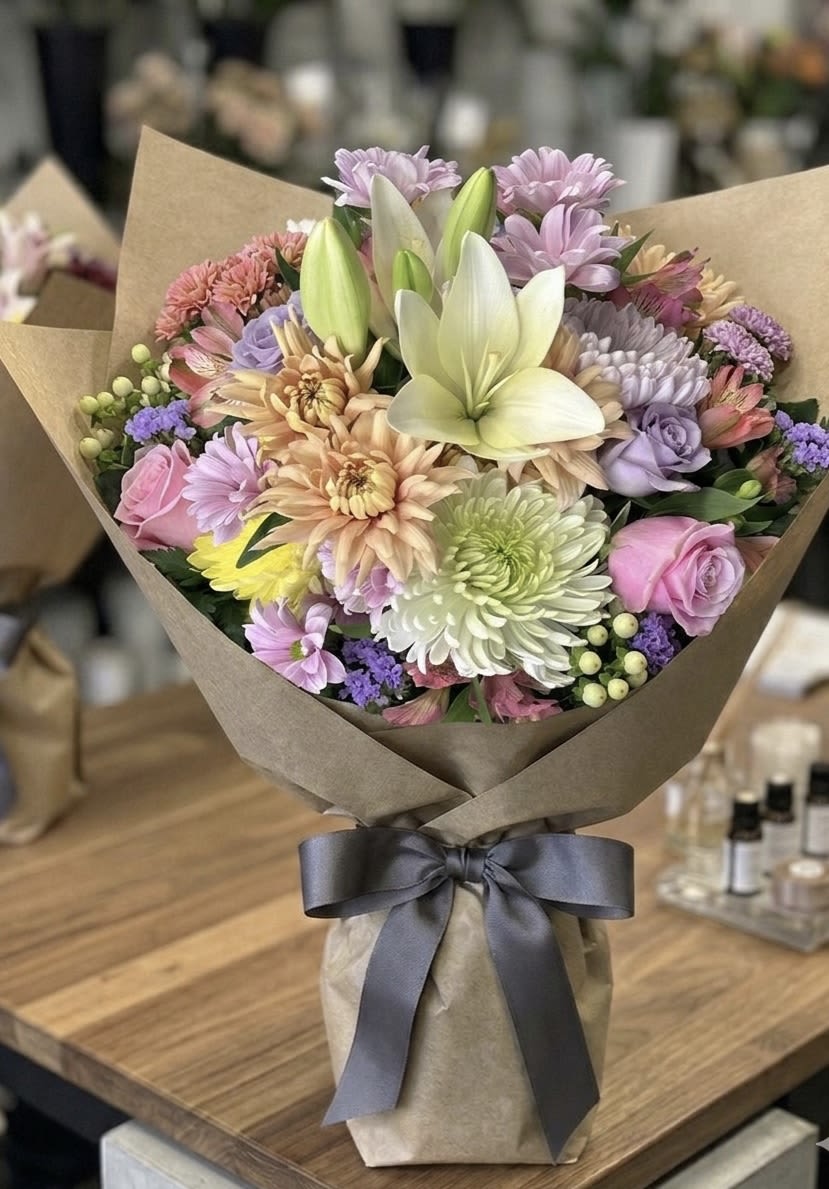 Mixed pastel bouquet with lilies and roses wrapped in brown paper