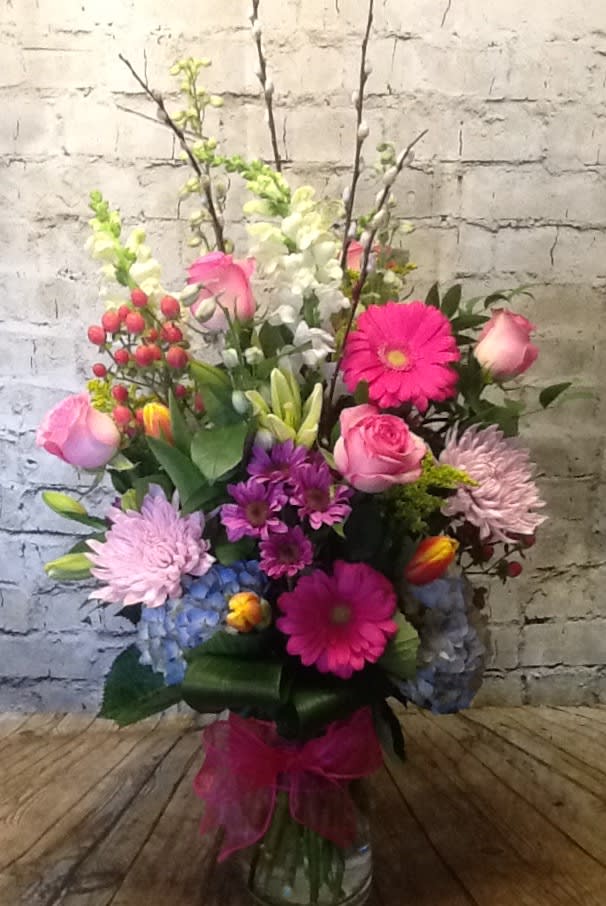 Spring Fever - Bright blooms in blue, pink, lavender and yellow. This tall glass cylinder features hydrangea, roses, tulips, gerbera daisies, pussy willow branches and more. 