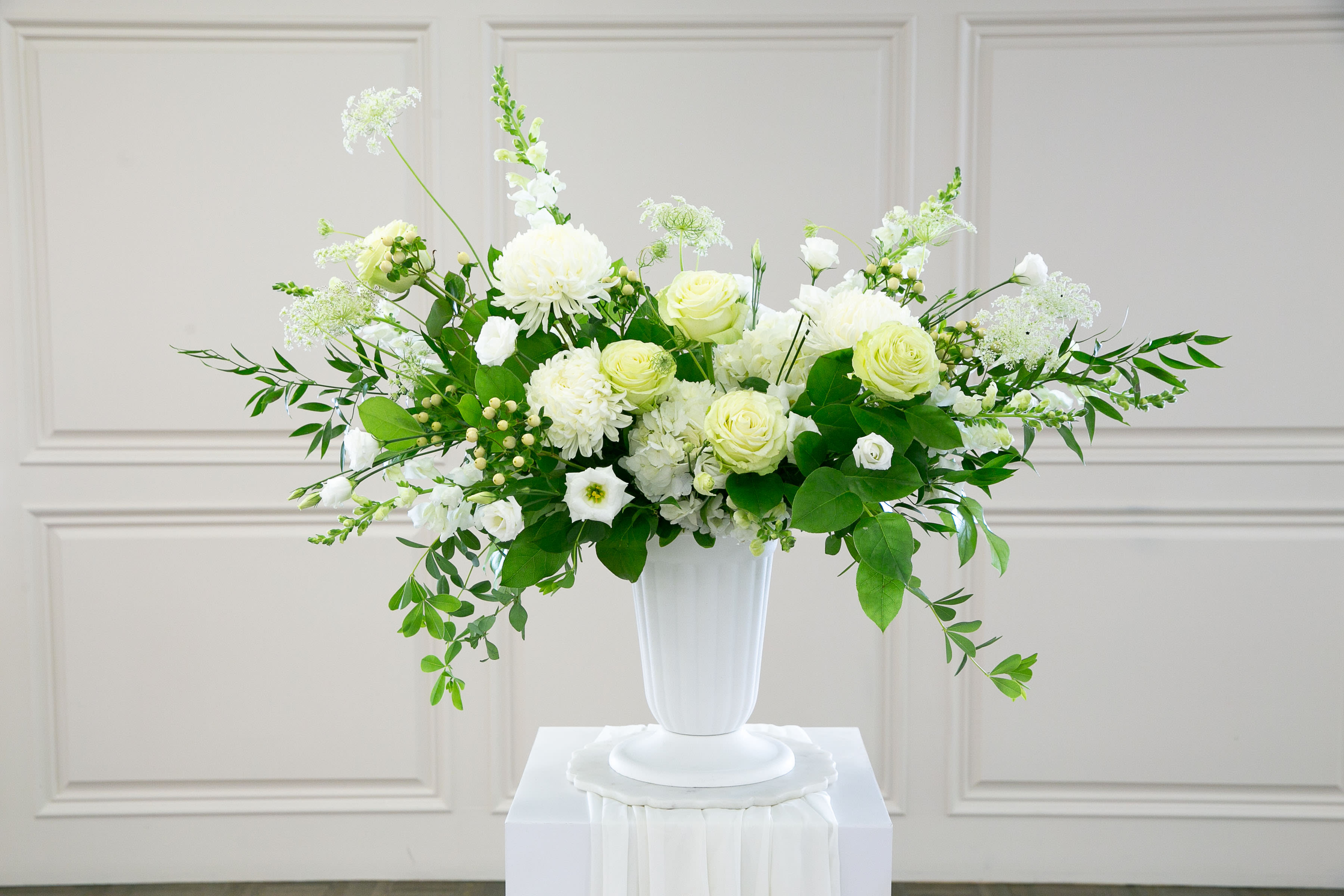 Always &amp; Forever White Sympathy Arrangement - Always &amp; Forever White Sympathy Arrangement (DELUX version shown)  Graceful, peaceful, and timeless, the Always &amp; Forever White Sympathy Arrangement is designed to honor a life beautifully lived while offering comfort to family and loved ones.  This elegant memorial design features a refined blend of premium white roses, spray roses, stock, Queen Anne’s lace, carnations, and seasonal white blooms, accented with fresh lush greenery for natural movement and soft texture. The classic all-white palette symbolizes peace, remembrance, and eternal love, making it a meaningful tribute for funeral services, memorial gatherings, or sending sympathy to grieving families.  Designed in a classic white pedestal vase, this arrangement brings a sense of serenity and quiet elegance to the memorial space.  All sympathy flowers are professionally designed at our floral studio in DeLand, Florida, and delivered throughout DeLand, Deltona, Orange City, Sanford, Lake Mary, and the greater Central Florida area.  This design is appropriate for: • Funeral services • Celebration of life ceremonies • Sympathy gifts sent to family homes • Memorial gatherings  Because we work with fresh seasonal flowers, some blooms may vary depending on availability. When substitutions are necessary, we carefully select flowers of equal beauty and value in the same color palette and design style.