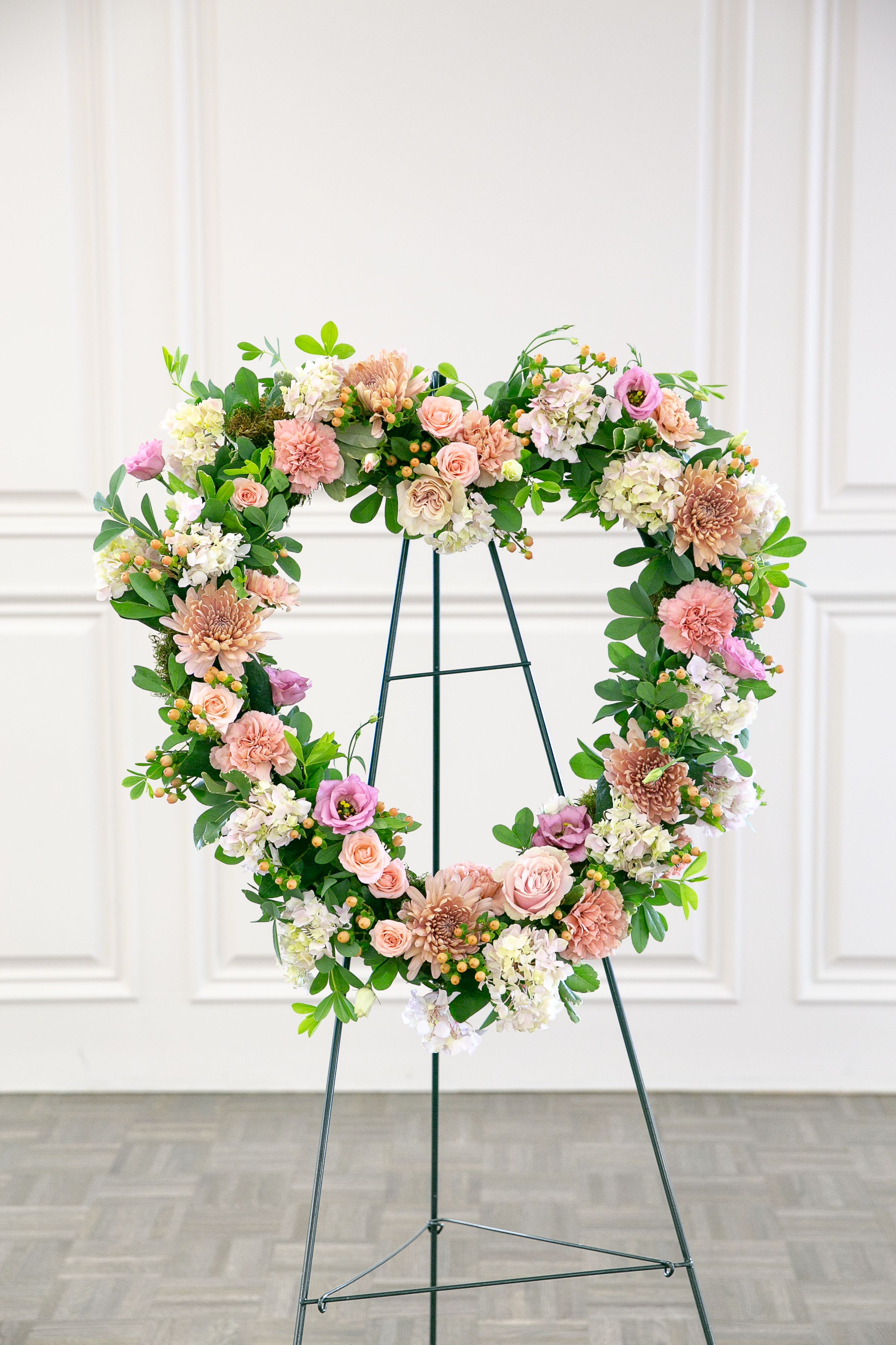 Blush Heart Tribute - Elegant and heartfelt, Blush Heart Tribute is a floral expression of love and remembrance designed to honor a cherished life.  This standing heart arrangement features a soft blend of blush, pink, and ivory blooms including roses, spray roses, hydrangea, and delicate seasonal flowers. Layers of premium blooms create a full, romantic design that conveys warmth, compassion, and enduring love.  Arranged in the classic heart shape and displayed on a standing easel, the design serves as a meaningful symbol of devotion and remembrance during memorial services and celebration-of-life gatherings. Soft greenery and textural accents add depth while preserving the gentle and refined aesthetic of the tribute.  Each piece is handcrafted by the designers at ImpeKable Flowers in DeLand, using carefully selected seasonal blooms sourced from premium growers.  A beautiful and meaningful tribute for honoring someone deeply loved.  Flower varieties may vary depending on seasonal availability while maintaining the same color palette and overall design style. 