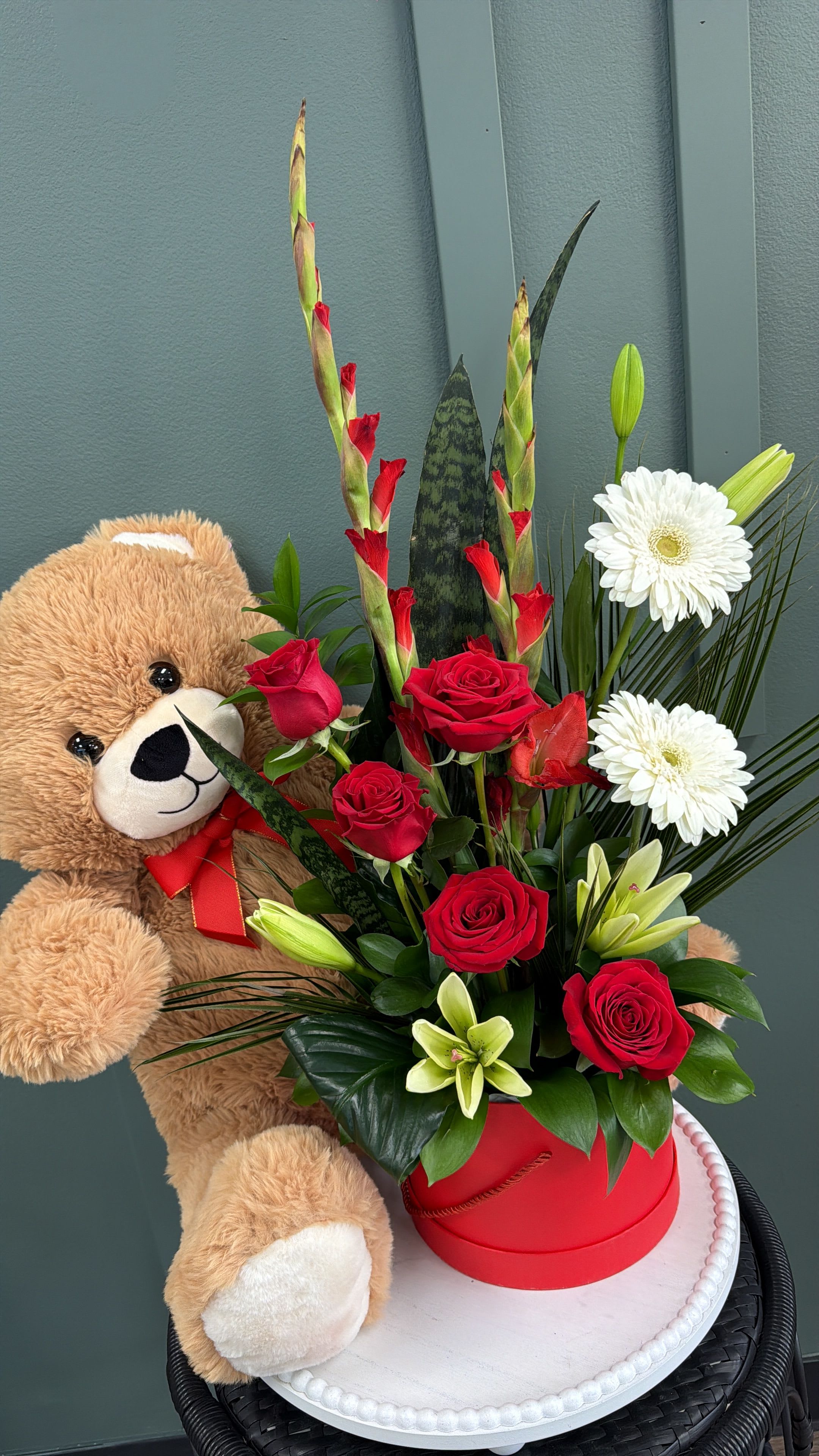 Red roses and white lilies in a red box with a teddy bear