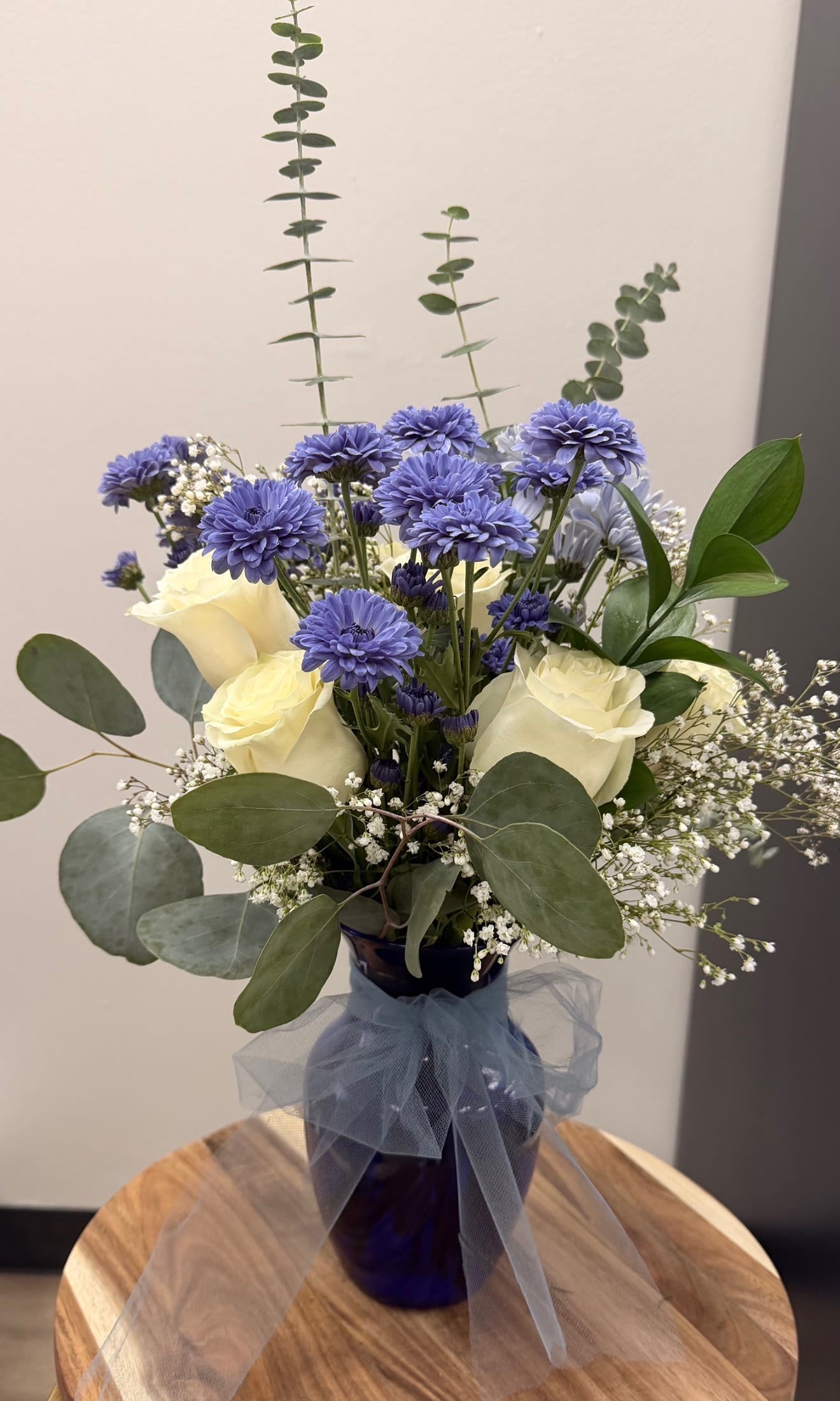 Blue and white bouquet in a dark vase with a tulle bow
