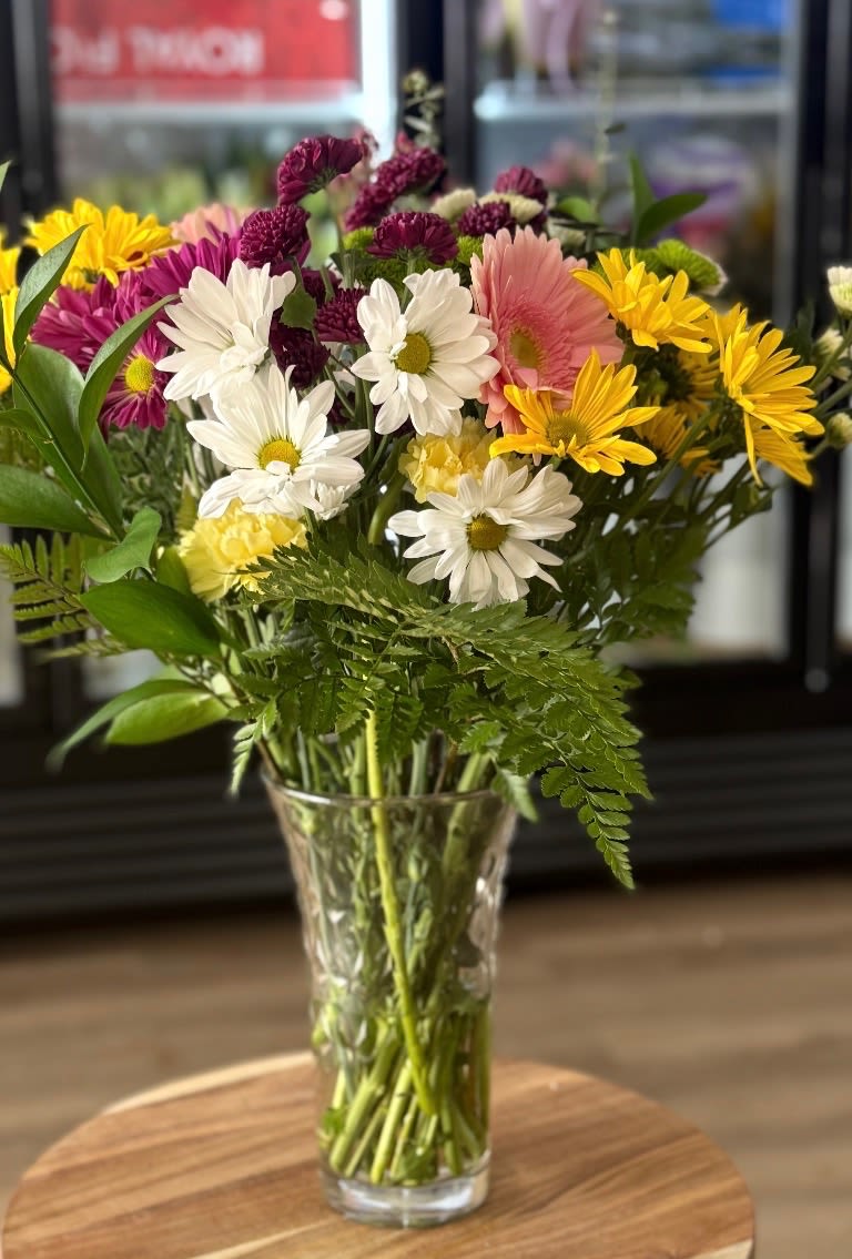 Mixed bouquet of daisies and chrysanthemums in a clear glass vase