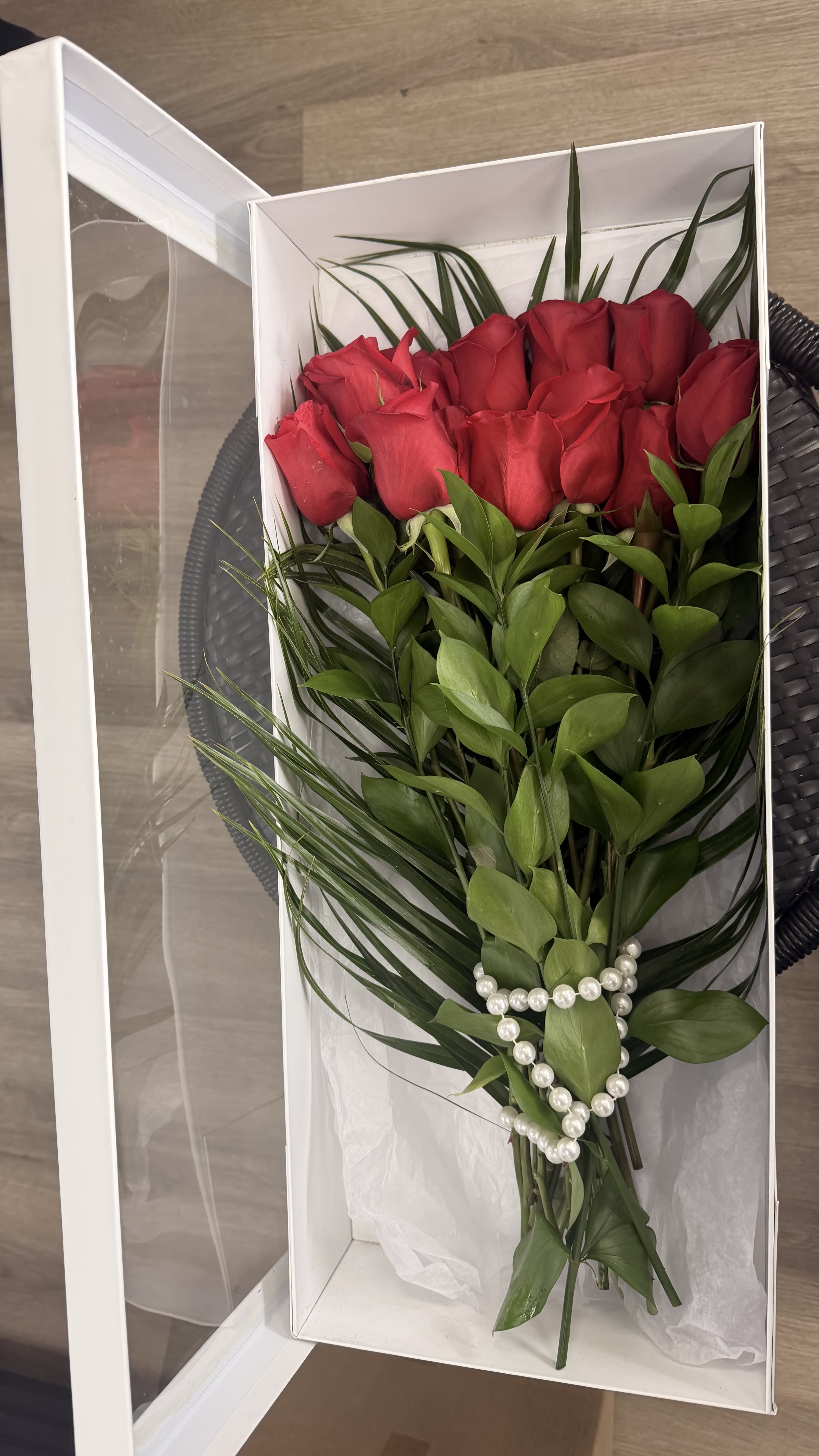 Red roses arranged in a white gift box with pearl accents
