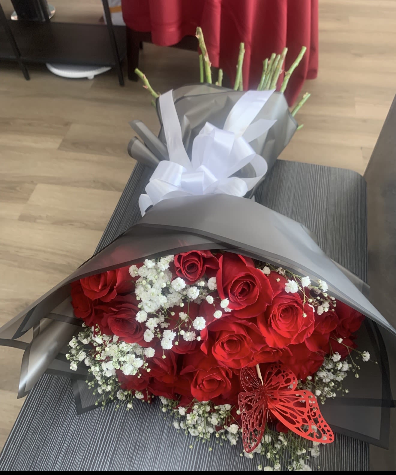 Bouquet of red roses with white baby's breath wrapped in gray paper