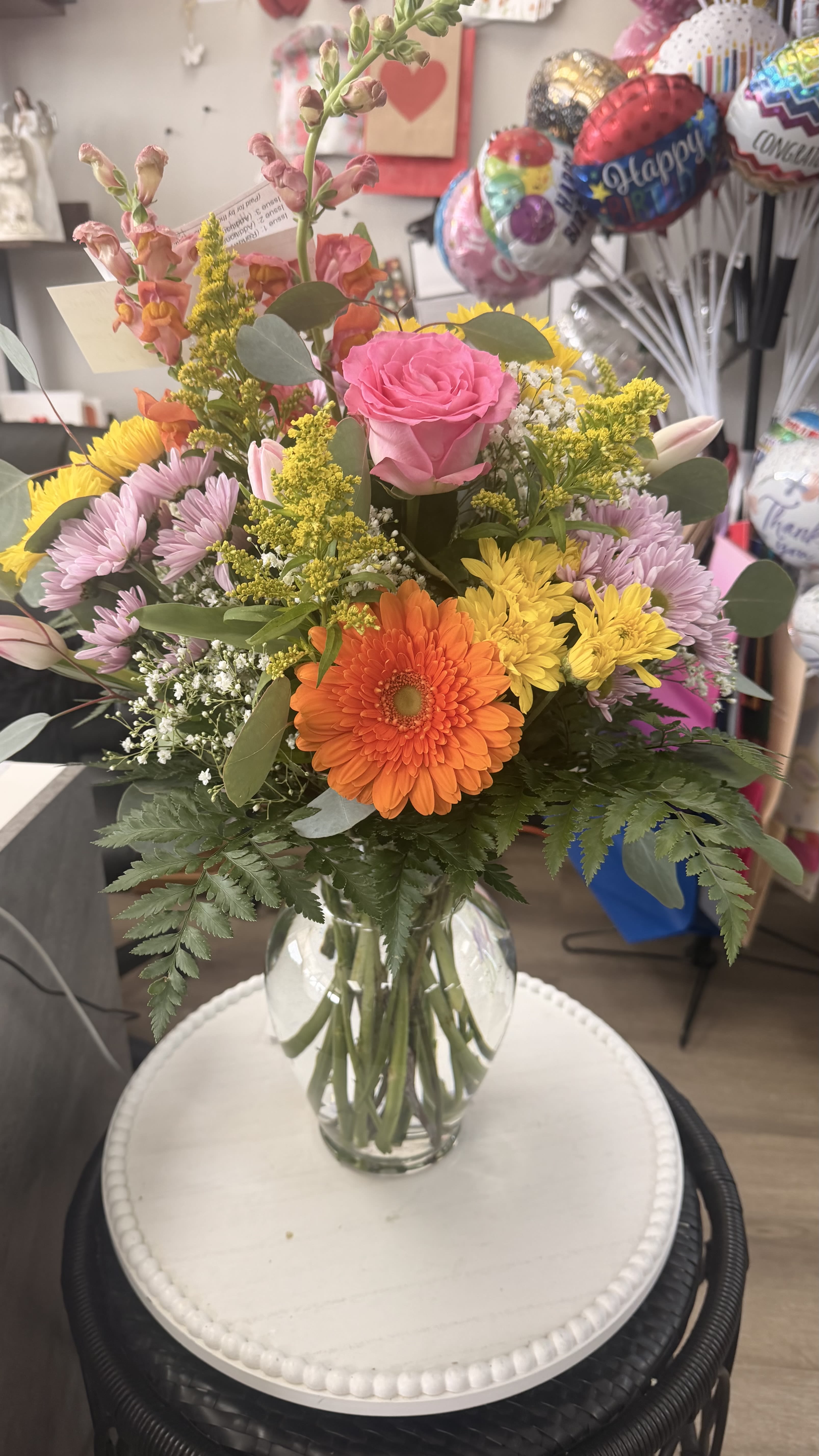 Mixed bouquet in a clear glass vase with pink, orange, yellow, and lavender flowers