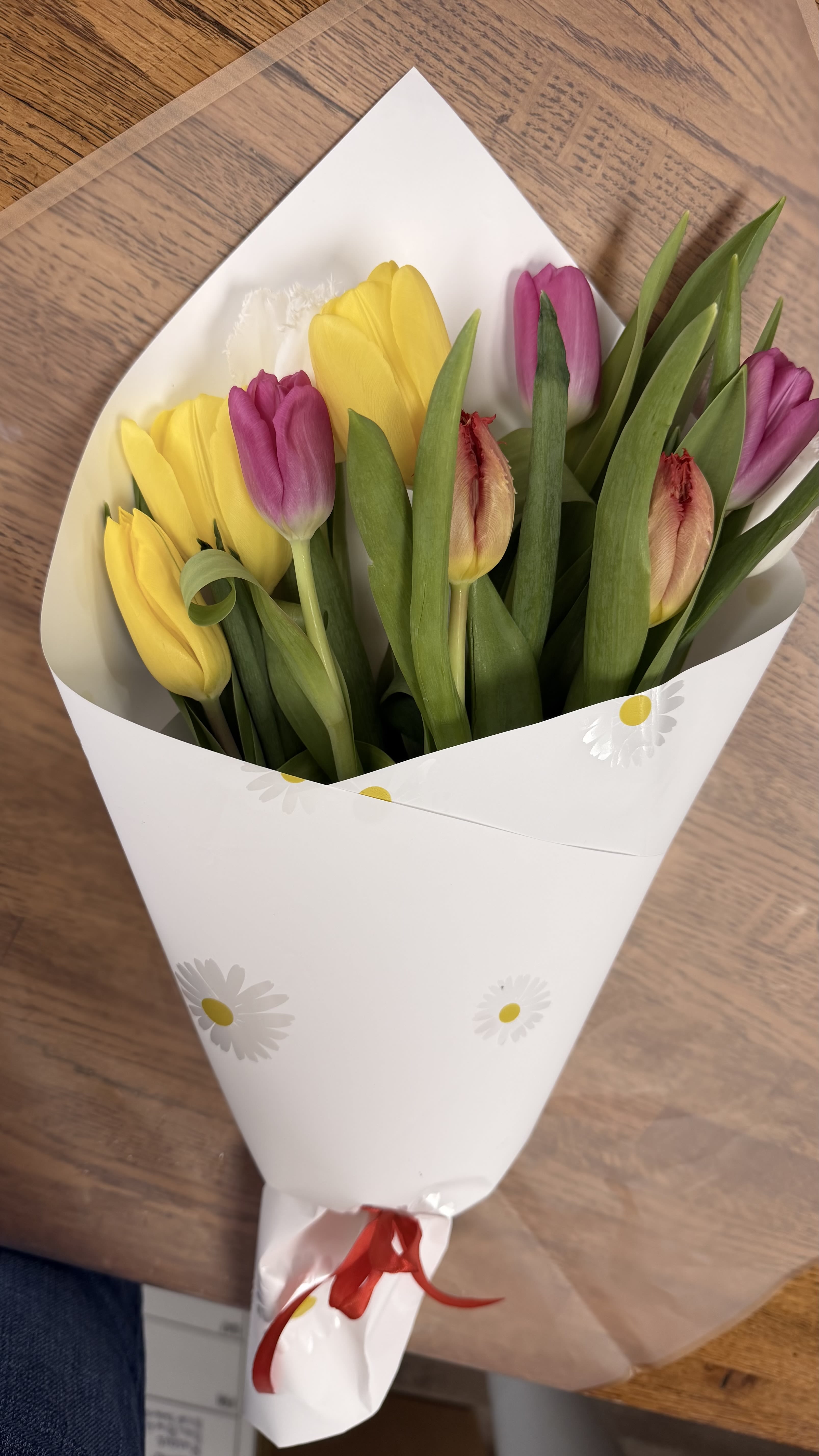 Bouquet of yellow and pink tulips wrapped in white paper