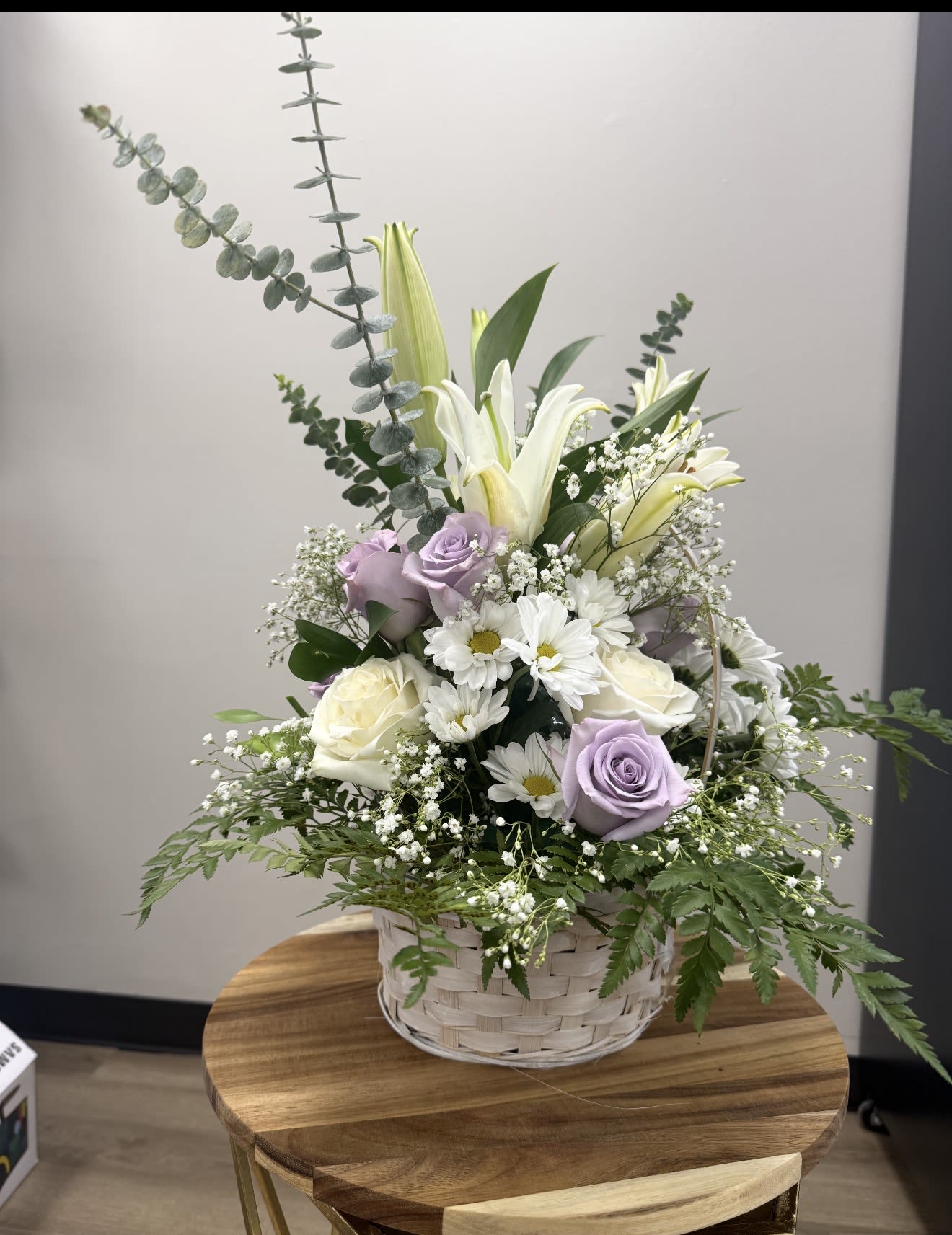 Basket arrangement with white lilies, lavender roses, and white daisies