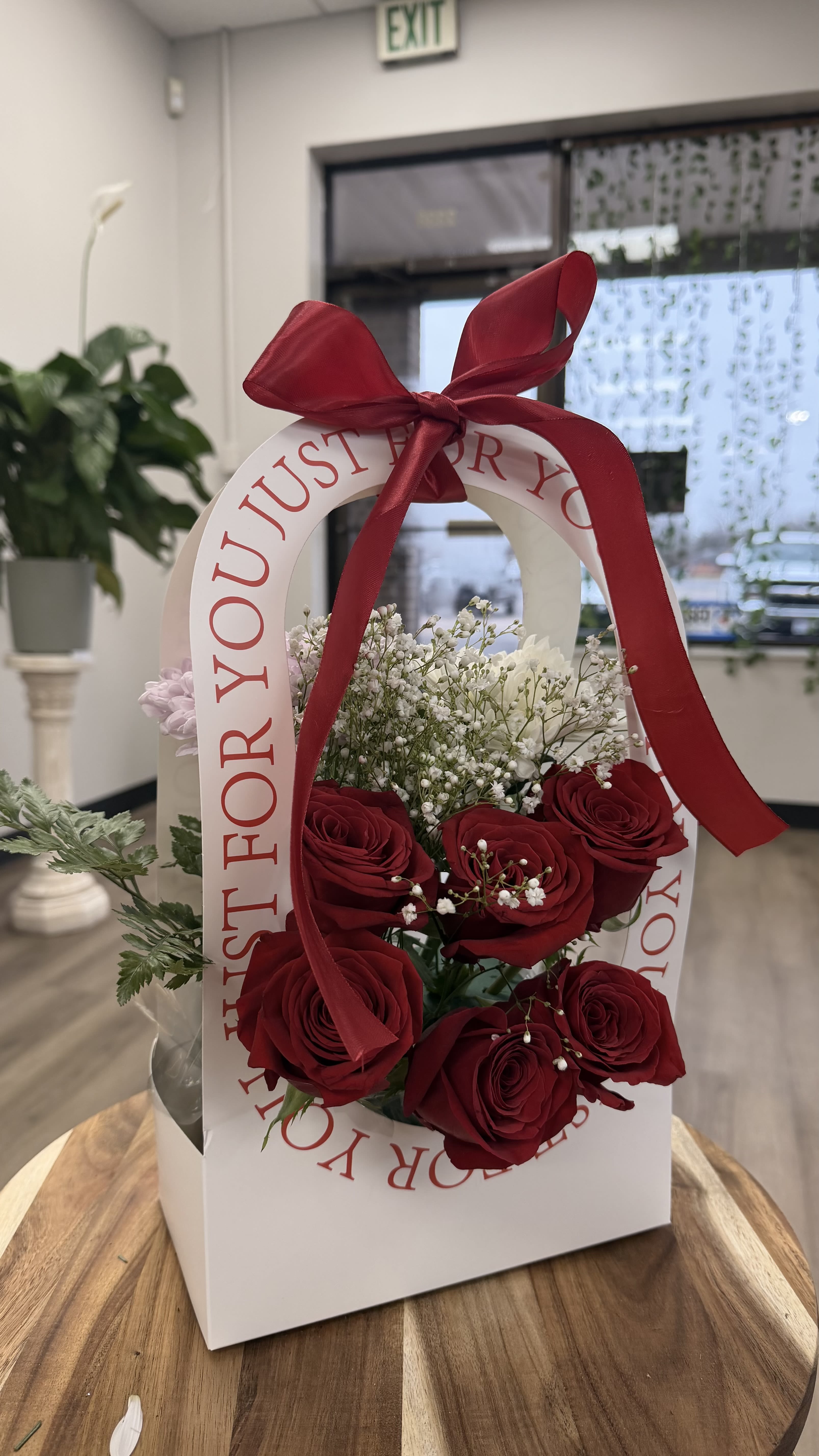 Red roses and baby's breath in a white gift bag with a red ribbon