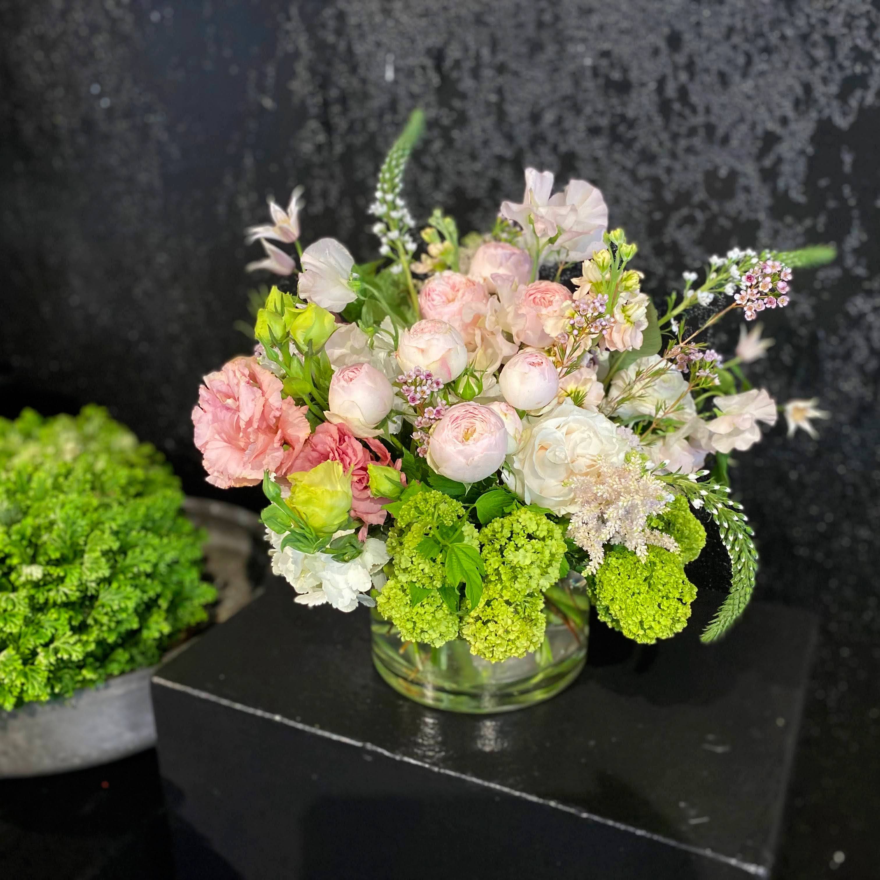 Bello - Bespoke selection of elegant and soft seasonal materials create a delicate expression of your love in this mounded but looser styled design. Made in approximately 6x6" container.