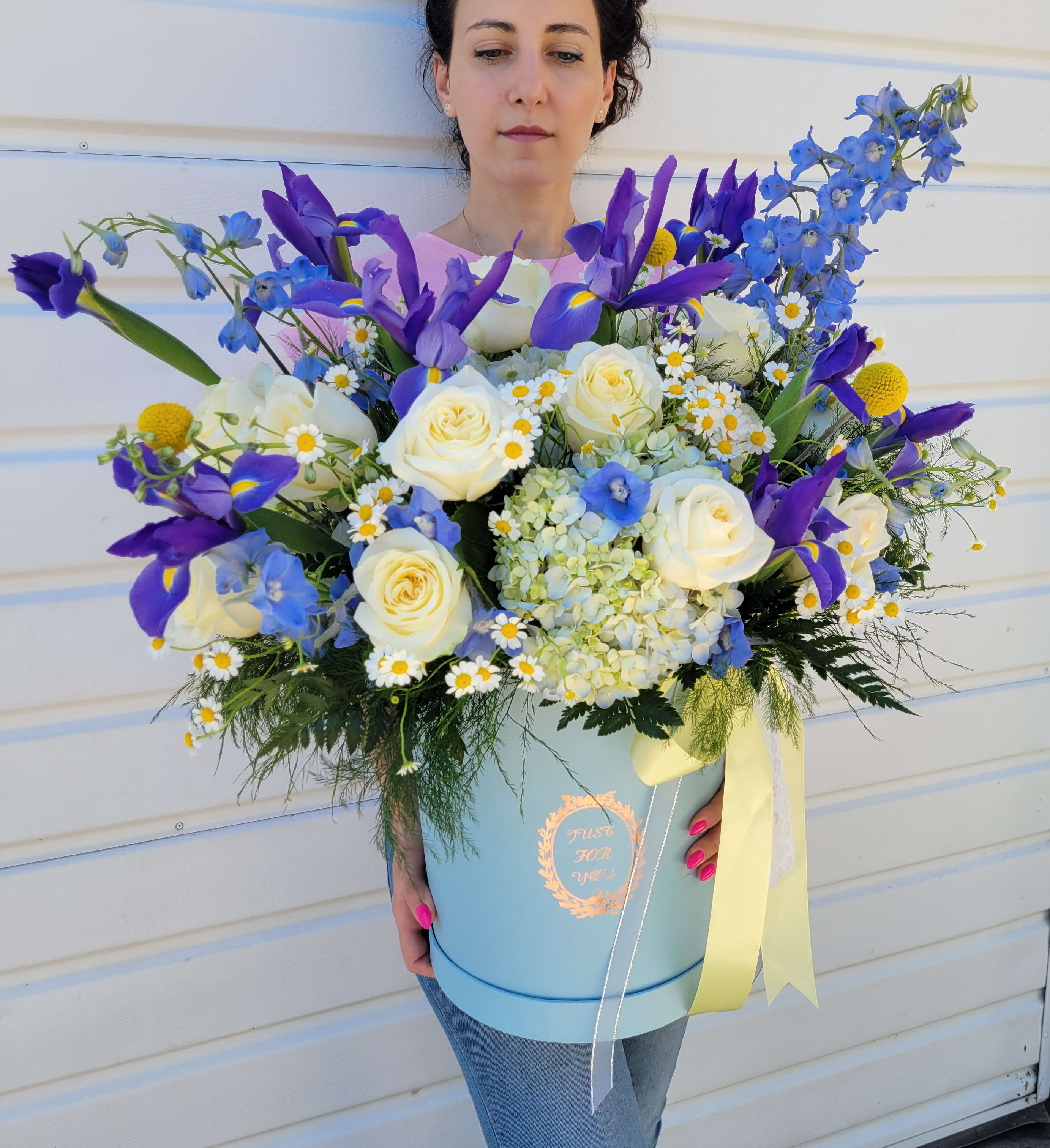 Sky Blue P - This vibrant flower arrangement combines cheerful Daisies, elegant Irises, romantic Roses, charming spray roses, and lush Hydrangeas, creating a lively display of color and texture.  The arrangement includes seasonal flowers. PREMIUM size is shown in the main picture.