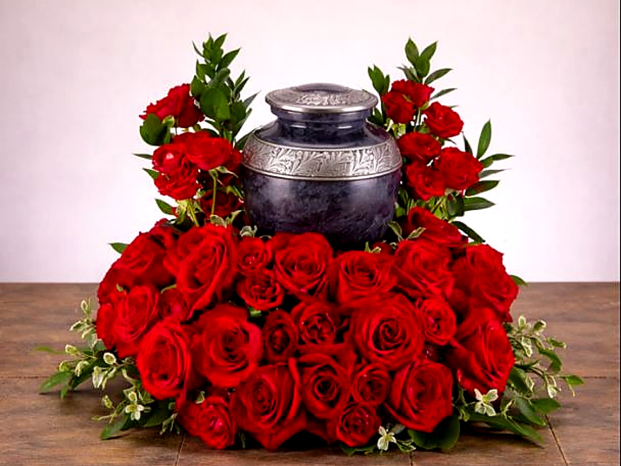 Always and Forever Arrangement – Red Rose Urn Tribute - The Always and Forever Arrangement from FloralFabulous is a deeply meaningful cremation urn tribute designed to express enduring love, devotion, and remembrance. This elegant arrangement features a luxurious display of rich red roses, beautifully arranged with lush greenery to create a full and timeless presentation.  Red roses symbolize deep love, respect, and everlasting connection, making this arrangement an especially powerful choice for honoring a spouse, partner, or cherished loved one. Designed to surround and frame a cremation urn, this piece creates a striking and emotional focal point during memorial services or celebrations of life.  Its classic and romantic design offers a heartfelt expression of sympathy while celebrating a life filled with love and meaningful memories. The fullness of the roses combined with soft greenery adds both elegance and warmth to the tribute.  FloralFabulous proudly provides cremation and sympathy flower arrangements in Round Rock, TX and the greater Austin area, helping families honor their loved ones with beauty, care, and compassion.