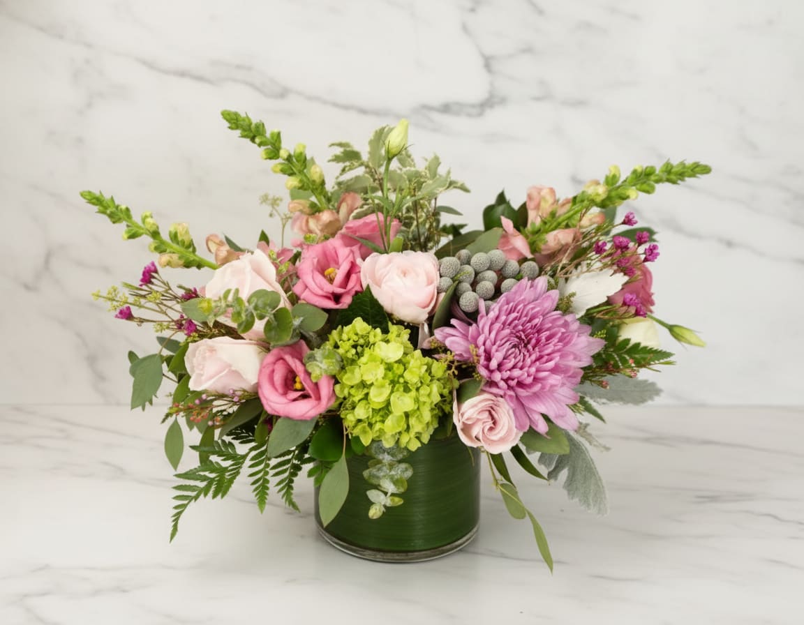 Blush Classic - A sophisticated beauty sure to bring joy to a friend or loved one.  Bursting with blushing roses and seasonal soft pink hued blooms, accented with soft greens and white florals. Image shown is deluxe size approx 10x12. 