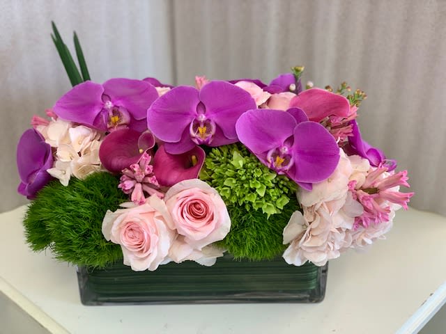 Classic Luxury - Rectangular container filled with all the colors of spring and the added twist of exotic orchids. Can be designed with mini-callas too... PLEASE NOTE: this design may require an few day's notice to ensure flower selection.