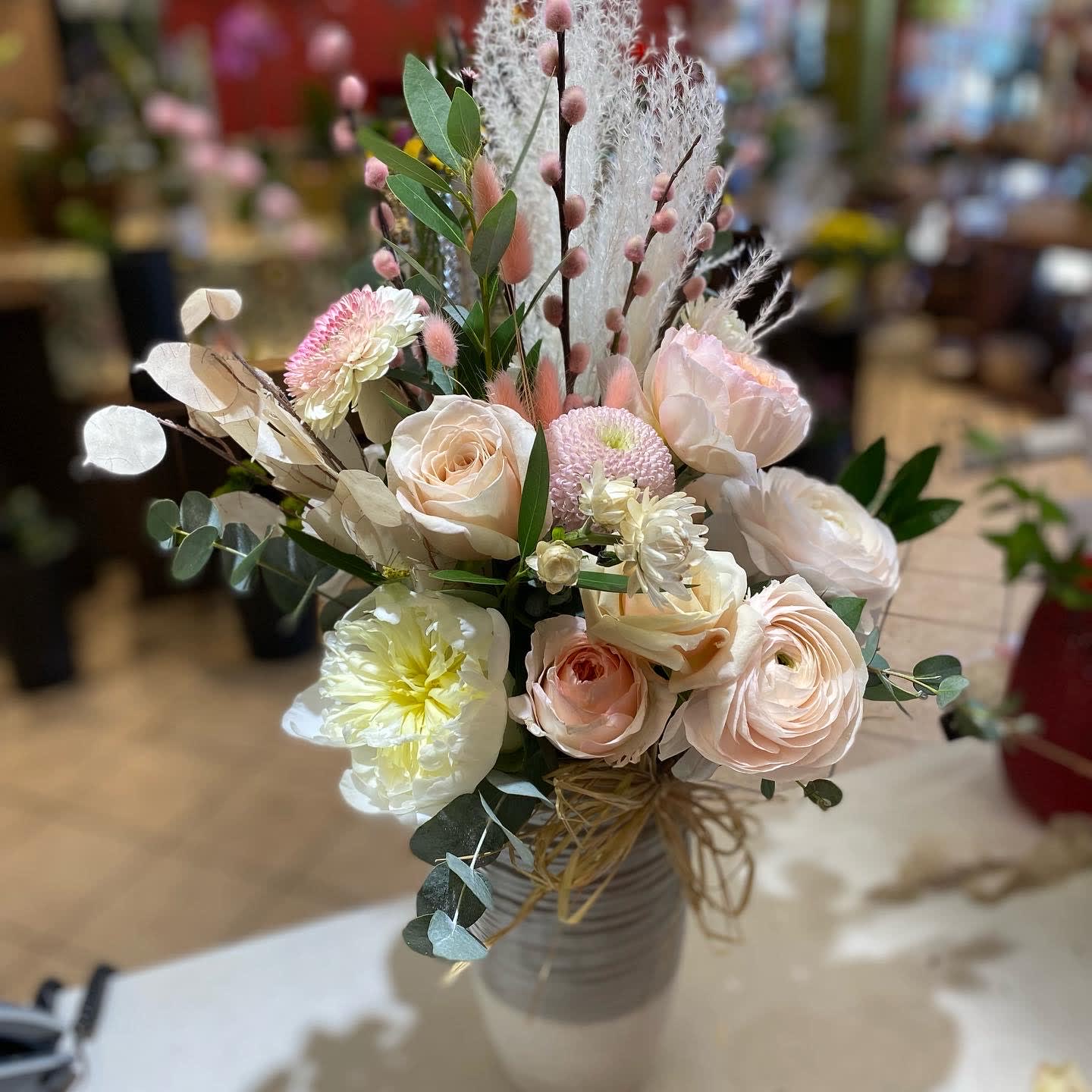 Bohemian Rhapsody - So many times design styles have popular names associated with them.  For instance, 'Boho Chic'.  This new arrangement is an example of a Boho Chic style..  The muted color palette, preserved grasses and pods and the unique ceramic vase work perfectly together.  Send this arrangement and you will be on trend like no other!