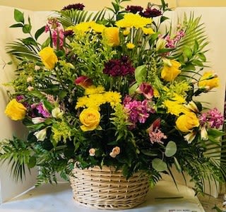 Spring Basket - Large woven basket overflowing with yellow roses, pink spray roses, purple blooms and green accents.