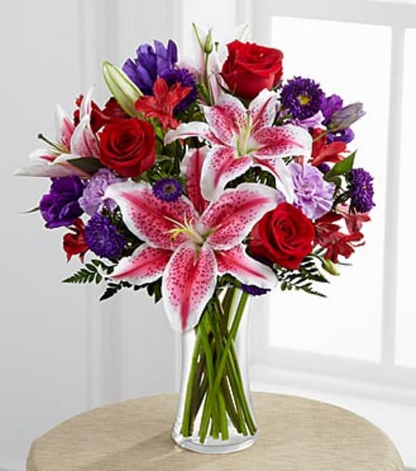 The Stunning Beauty™ Bouquet by FTD® - VASE INCLUDED - The Stunning Beauty™ Bouquet by FTD® is an absolutely lovely way to send your love and affection across the miles. Fragrant Stargazer lilies stretch their star-like petals across a bed of rich red roses, lavender carnations, red Peruvian lilies, purple double lisianthus, purple matsumoto asters and lush greens. Presented in a classic clear glass vase, this elegant bouquet is an incredible way to convey your sweetest sentiments. GOOD bouquet is approximately 18"H x 15"W. BETTER bouquet is approximately 20"H x 17"W. BEST bouquet is approximately 20"H x 17"W.  Lilies may arrive in various stages of development. The lily blooms will continue to open, extending arrangement life - and your recipient's enjoyment. Your purchase includes a complimentary personalized gift message.