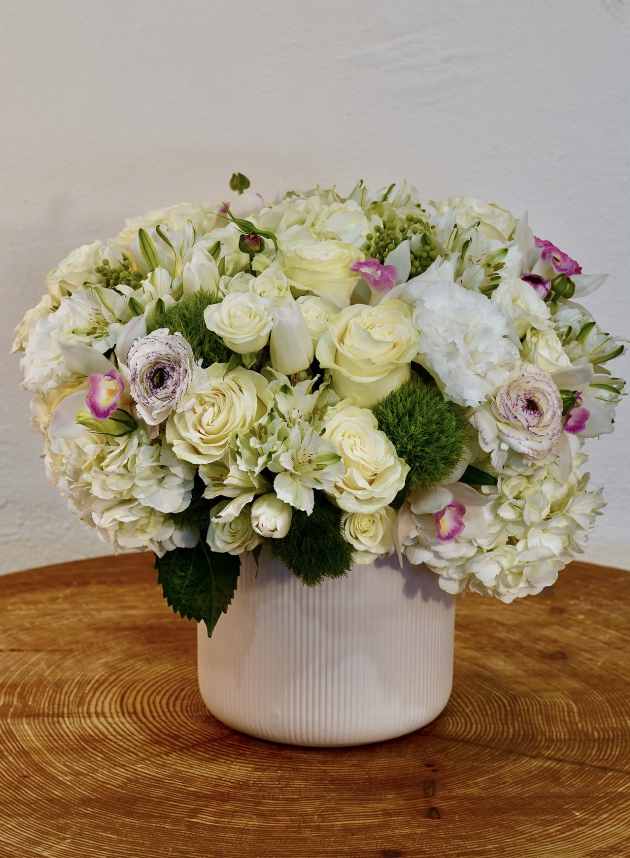 White Garden - A beautiful and elegant white garden-style floral arrangement featuring hydrangea, roses, and delicate seasonal blooms arranged with fresh greenery in a modern ceramic vase. This timeless design brings softness, elegance, and natural beauty to any home, office, or special occasion. Perfect as a thoughtful gift or as a stylish centerpiece. We offer same-day flower delivery in Beverly Hills, West Hollywood, Santa Monica, Beverly Grove, Bel Air &amp; Culver City. Order online or call now for fast delivery today. The arrangement shown in the photo reflects our Deluxe size, featuring a fuller, more abundant design with premium blooms.