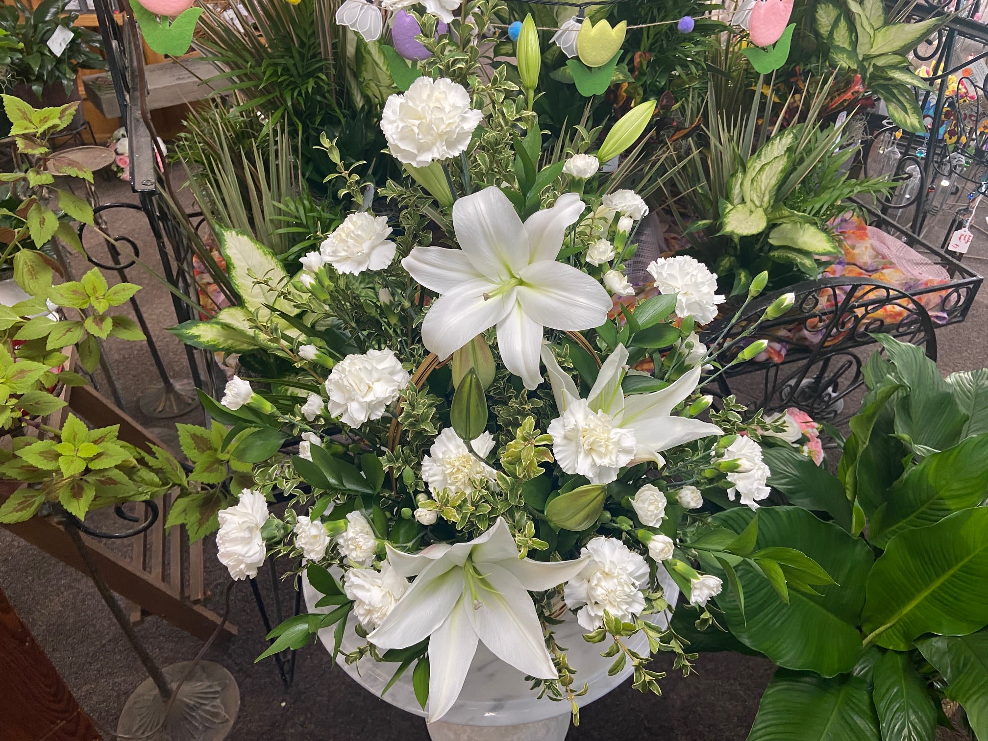 Peaceful White Lilies Basket - When you send this beautiful arrangement to the service all will appreciate its elegance and grace. The contrast of brilliant white blossoms and dazzling greenery create a wonderfully calm and dignified setting. Gorgeous flowers such as white lilies carnations and miniature carnations mix with vibrant greens in a large basket. Simply stunning. Orientation: One-Sided 