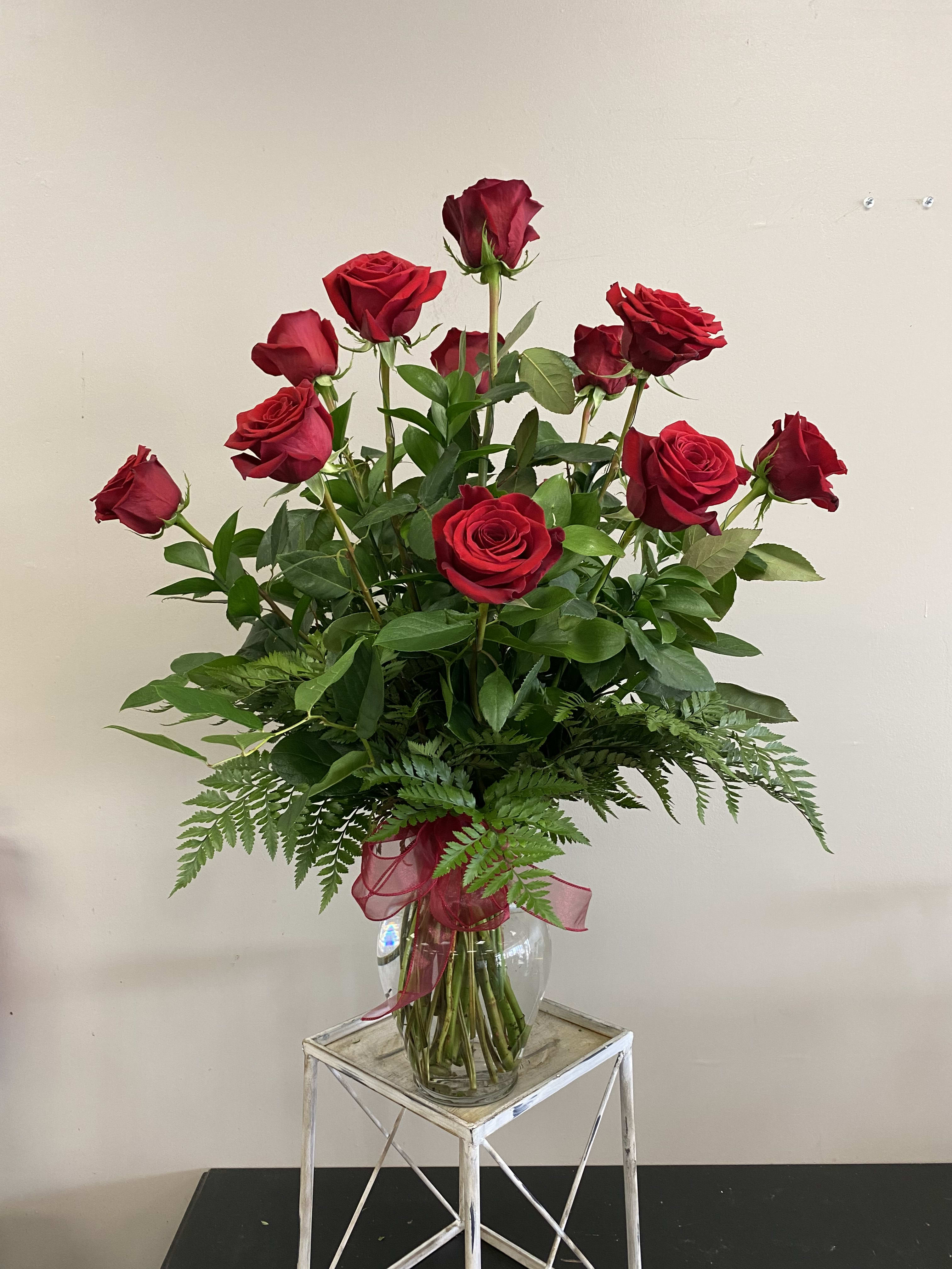 Dozen Long Stem Red Roses  - A dozen long stem red roses with assorted greenery in a clear glass vase. These roses are the perfect gift for anniversaries, birthdays, retirement, or even just because! Order for a same day or next day delivery and give us a call if you want custom flowers.   