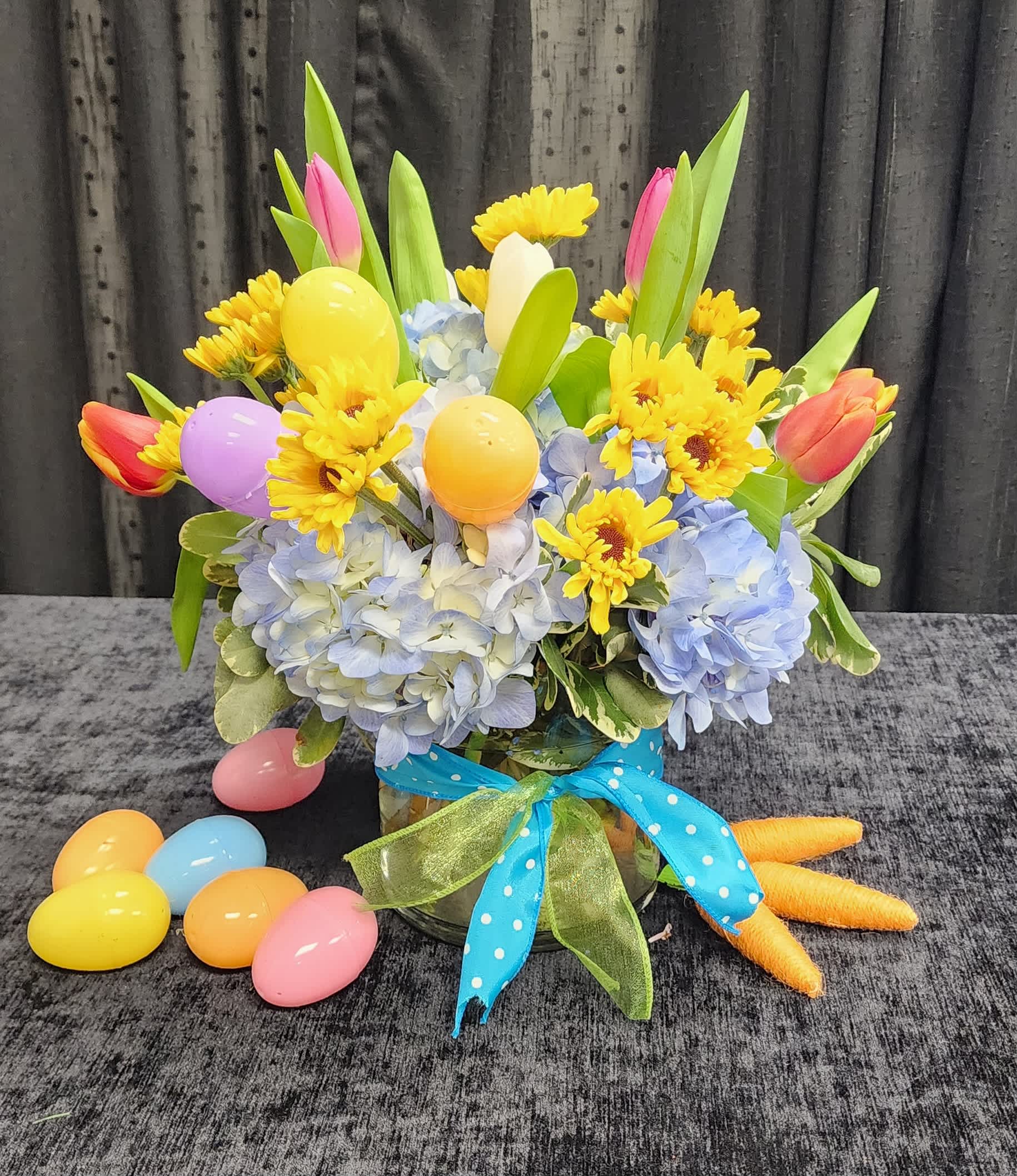 Easter Bunny Eggs - A spring arrangement with hydrangea, assorted tulips and pomps with a hidden stash of Easter eggs.  