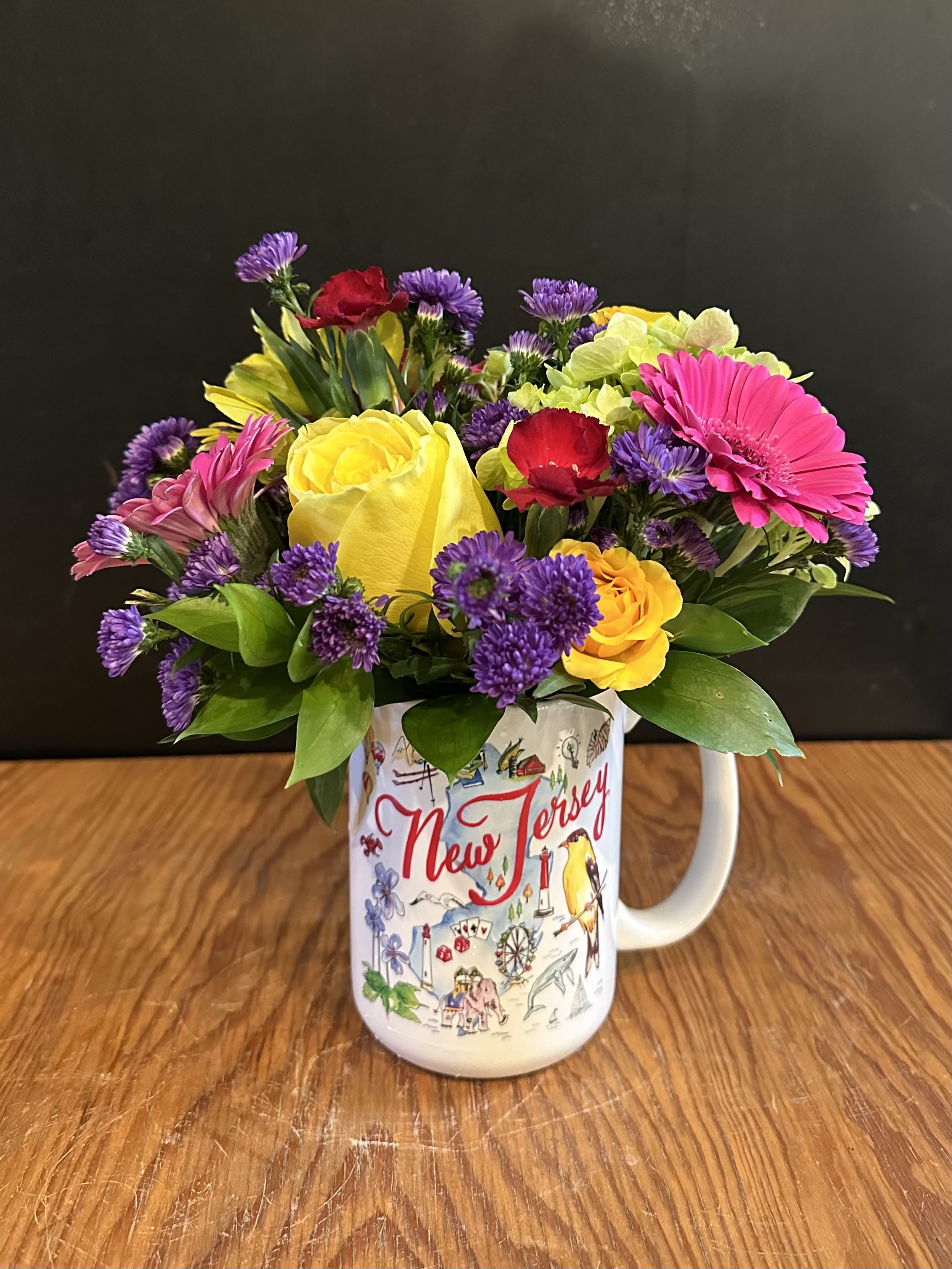 New Jersey Mug Arrangement - Celebrate local charm with this beautifully designed New Jersey-themed ceramic mug, filled with a vibrant mix of fresh, seasonal flowers. Once the flowers are enjoyed, the keepsake mug makes a wonderful everyday reminder of the Garden State.  