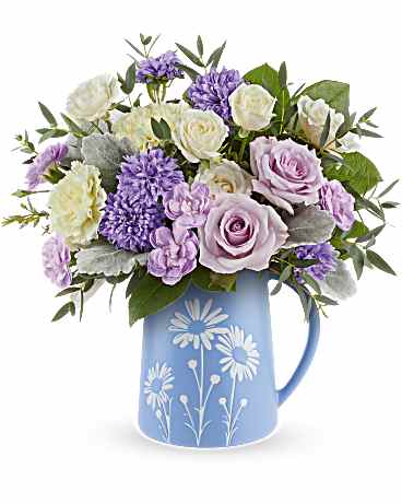 Daisy Haze Bouquet - Soft and whimsical, Daisy Haze Bouquet captures pastel perfection with lavender roses, yellow carnations, and crème spray roses arranged in a blue food-safe pitcher adorned with a charming white daisy design. Daisy Haze Bouquet features lavender roses, crème spray roses, light yellow carnations, lavender miniature carnations, dusty miller, parvifolia eucalyptus, and lemon leaf, arranged in  Daisy Dreams Pitcher, which meets FDA-approved to safely serve and store food. Approximately 13 1/2" W x 14" H
