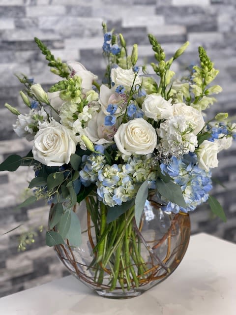 Blooming Sea - A breathtaking array of blue hydrangeas, soft white garden roses, light blue delphinium, delicate lisianthus, and vibrant snapdragons, all artfully arranged with rustic foliage for a naturally charming touch. This unique composition brings a timeless and serene beauty to any setting.