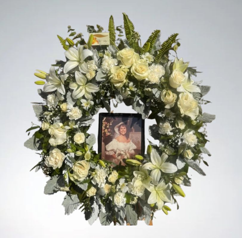 In Loving Memory Wreath  - A timeless circle of peace and remembrance, this all-white mixed wreath surrounds a cherished photo in the center—offering a heartfelt tribute filled with grace and love