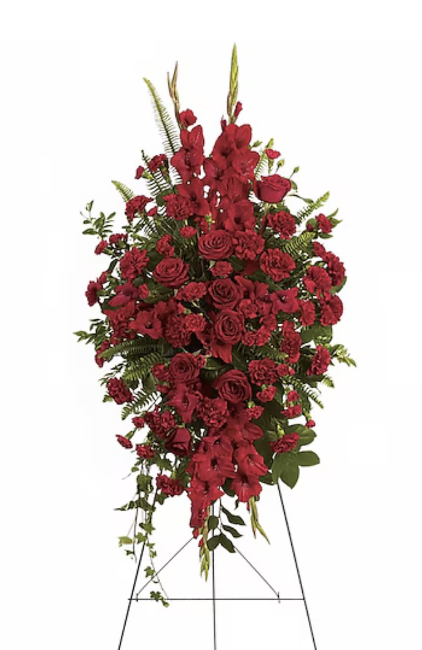 Ruby Radiance Tribute Spray  - This striking spray features a bold combination of red roses, carnations, and gladiolus, creating a powerful and elegant tribute. Its deep crimson tones symbolize love, respect, and remembrance, making it perfect for honoring a cherished life with passion and grace.