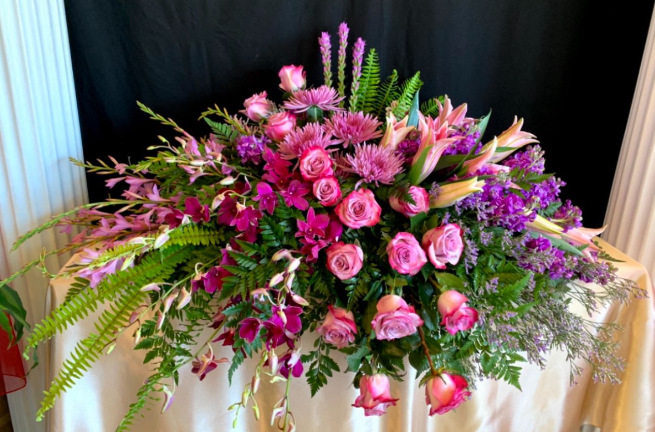 Heavenly Orchid Casket  - A tropical and romantic mix of fresh orchids, roses, and lilies in vibrant pink and purple hues. This heavenly arrangement celebrates a life filled with love, grace, and beauty.