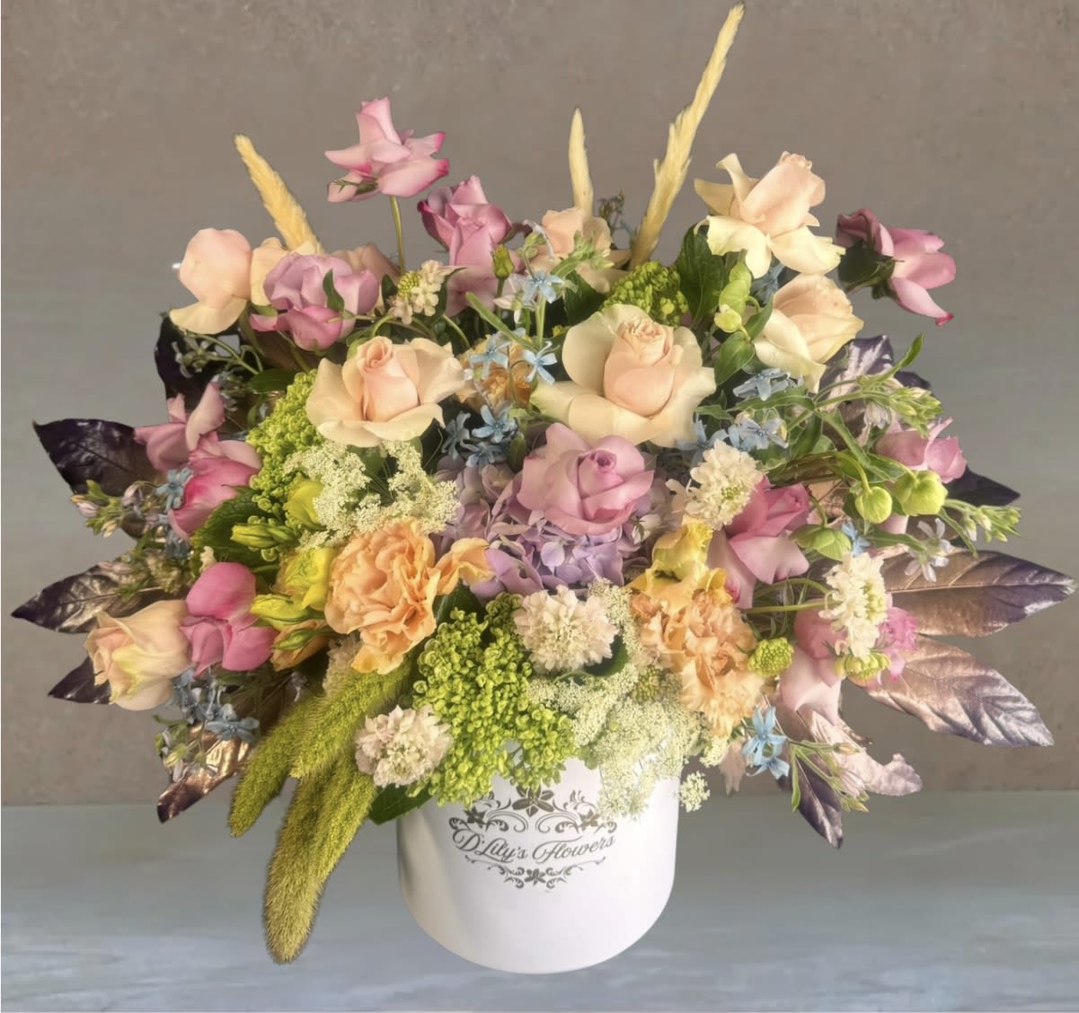 Whimsical Garden by D'Lily's Flowers  - A dreamy mix of soft pink, lavender, peach, and green blooms, including roses, carnations, Queen Anne's lace, and touches of dried pampas grass. Bursting with color and texture, this arrangement feels like a walk through an enchanted spring meadow.