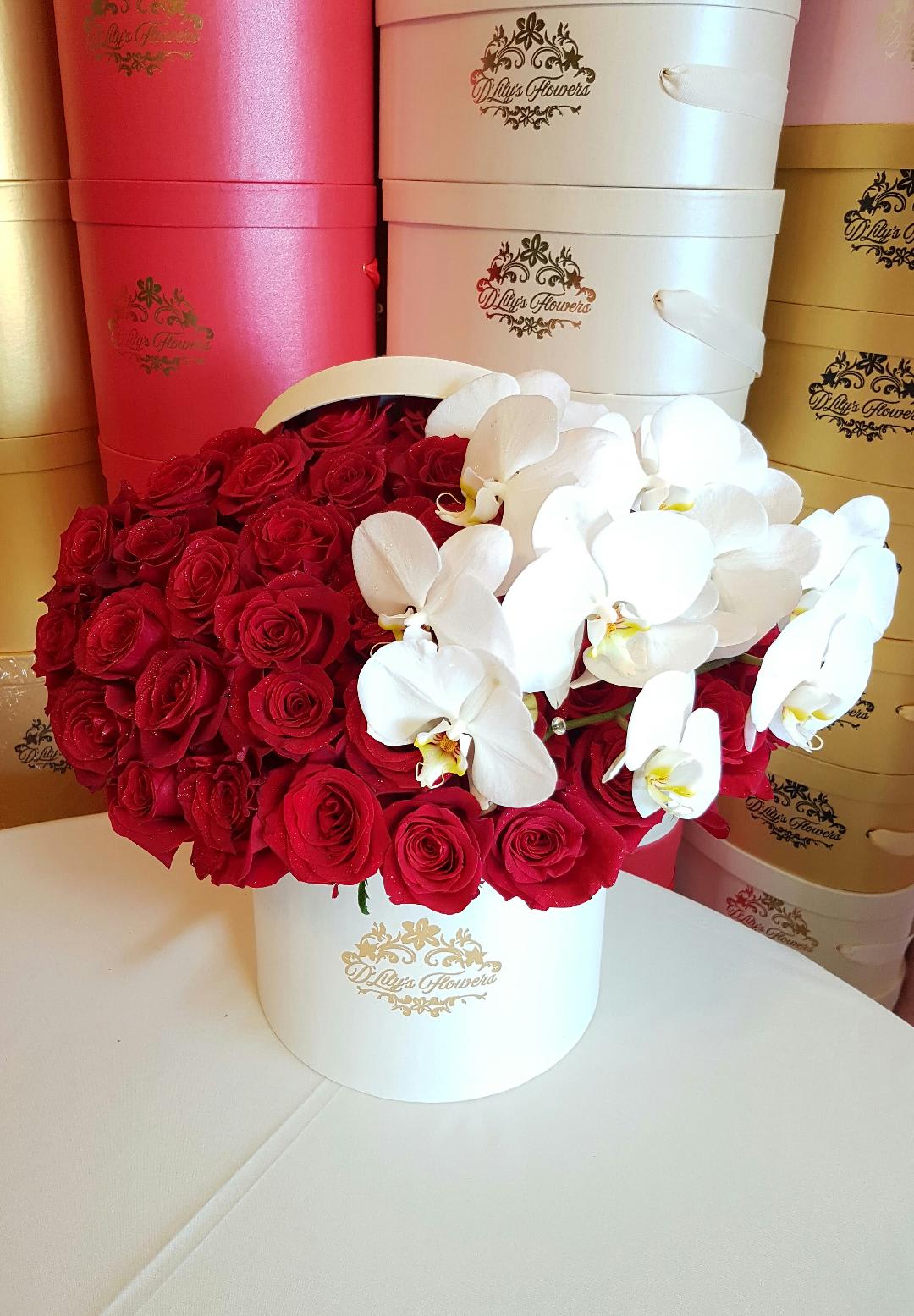 Orchid Round Box  by D'Lily's Flowers  - These designs are not only on social media but at D' Lily's Flowers.This beautiful modern arrangement is full of red roses and amazing orchid stems on top. Picture displayed is deluxe size and it has 3 dozen roses. 