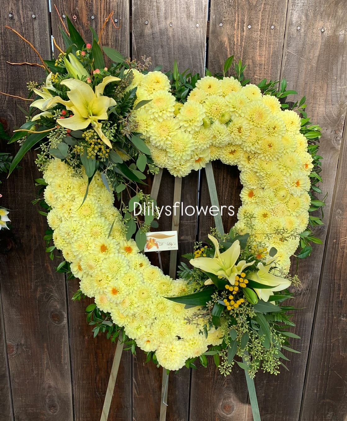 Forever in Yellow Heart  - This heartfelt arrangement features vibrant yellow carnations, known for their enduring love and admiration, paired beautifully with elegant yellow lilies, symbolizing purity, renewal, and the restored innocence of the soul. Together, these blooms convey warmth, remembrance, and a gentle farewell, wrapped in the comforting glow of yellow.