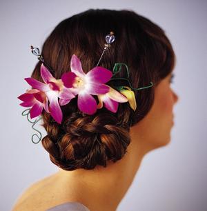 Woman wearing a purple orchid hairpiece in an updo