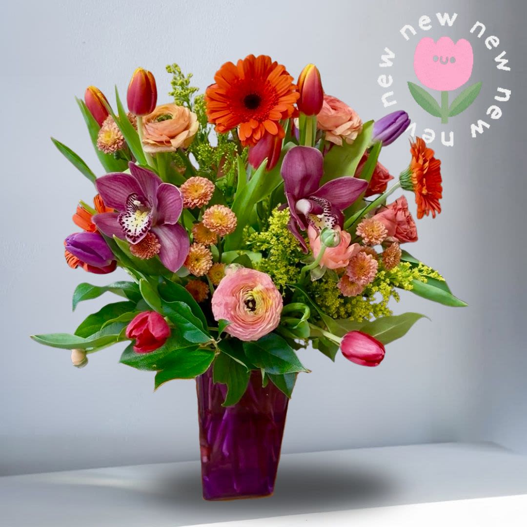 Electric Feel - A vibrant, mood-lifting arrangement designed to celebrate color and joy. This bright seasonal design features a lively mix of tulips in assorted hues, paired with lush ranunculus and spray roses, elegant cymbidium orchids, and pops of vivid orange gerbera daisies. Perfect for birthdays, celebrations, or a thoughtful pick-me-up—especially for anyone who loves tulips.