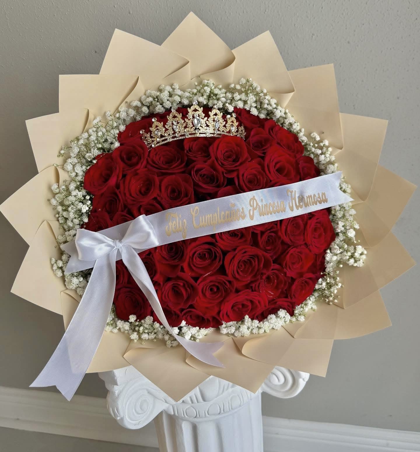Royal  Rose  Crown Bouquet - Celebrate her special day with our Royal  Rose Crown Bouquet, an elegant arrangement designed to make any birthday girl feel like true royalty. This luxurious bouquet features a stunning bed of premium red roses framed with delicate baby’s breath and wrapped in soft cream petals for a flawless finish. Topped with a sparkling golden crown and personalized with a satin ribbon message, this arrangement is perfect for princesses of all ages.