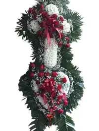 DOUBLE SPRAY HEART AND CROSS - A dignified standing tribute that speaks of faith and remembrance, this sympathy flower arrangement combines a white floral cross layered over a matching white heart for a powerful, reverent display. The double spray heart and cross is ideal for funerals or memorial services where you want to honor religious sentiment and offer comfort to the bereaved.  Deep green foliage forms a lush, elongated easel backing while clusters of red roses and delicate white filler blooms gather at the center of the cross and along the heart, punctuated with red ribbon bows for contrast. The vertical silhouette and dense greenery give it the presence expected of a traditional funeral spray, designed to be displayed upright on an easel.  Made to console the person you're honoring, this arrangement communicates love, faith, and respect-appropriate for family memorials, church services, or a graveside tribute. It arrives ready to place on an easel; please contact us for delivery timing and any personalization requests so we can ensure it reflects your sentiments.