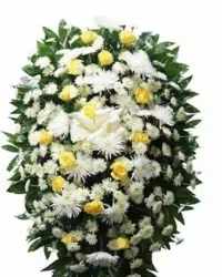 PREMIUM STANDING SPRAY YELLOW AND WHITE WITH ROSES - Soft white chrysanthemums and Roses form a calm, oval spray punctuated by gentle yellow roses-an elegant sympathy standing spray designed to convey heartfelt remembrance. As a funeral or memorial arrangement, this yellow and white standing spray expresses solemn respect and quiet comfort for the person you're honoring.  Densely arranged white blooms create the main body while soft pops of yellow roses add warm contrast against dark green foliage that frames the elongated silhouette. The classic mix of roses, chrysanthemums, and lilies gives both texture and a dignified presence suitable for a casket-side tribute or easel display; sizing and delivery options are available at checkout to ensure it arrives ready for placement.