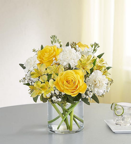 176259 Yellow and white delight - Full of sunny cheer, our brightly-colored bouquet makes the kind of surprise that will leave them smiling. Blooms of yellow and white are loosely gathered with lush greenery inside a clear cylinder vase. Perfect for delivering warm sentiments to someone who means so much.