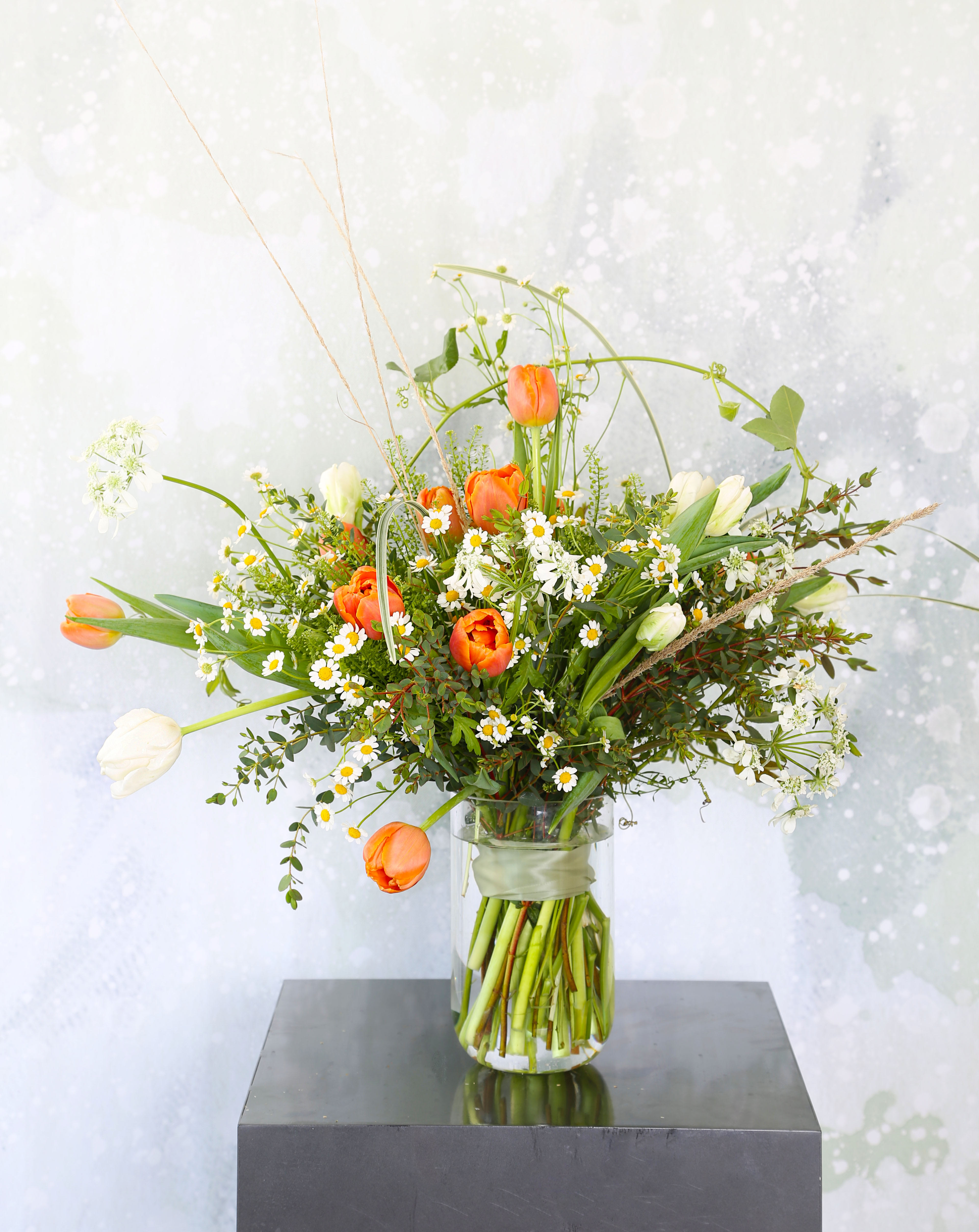 Spring Tulip - An adorable wild flower style bouquet create by Orange and Ivory tulip and mix with seasonal bloom and green. This arrangement come with 7" tall vase.