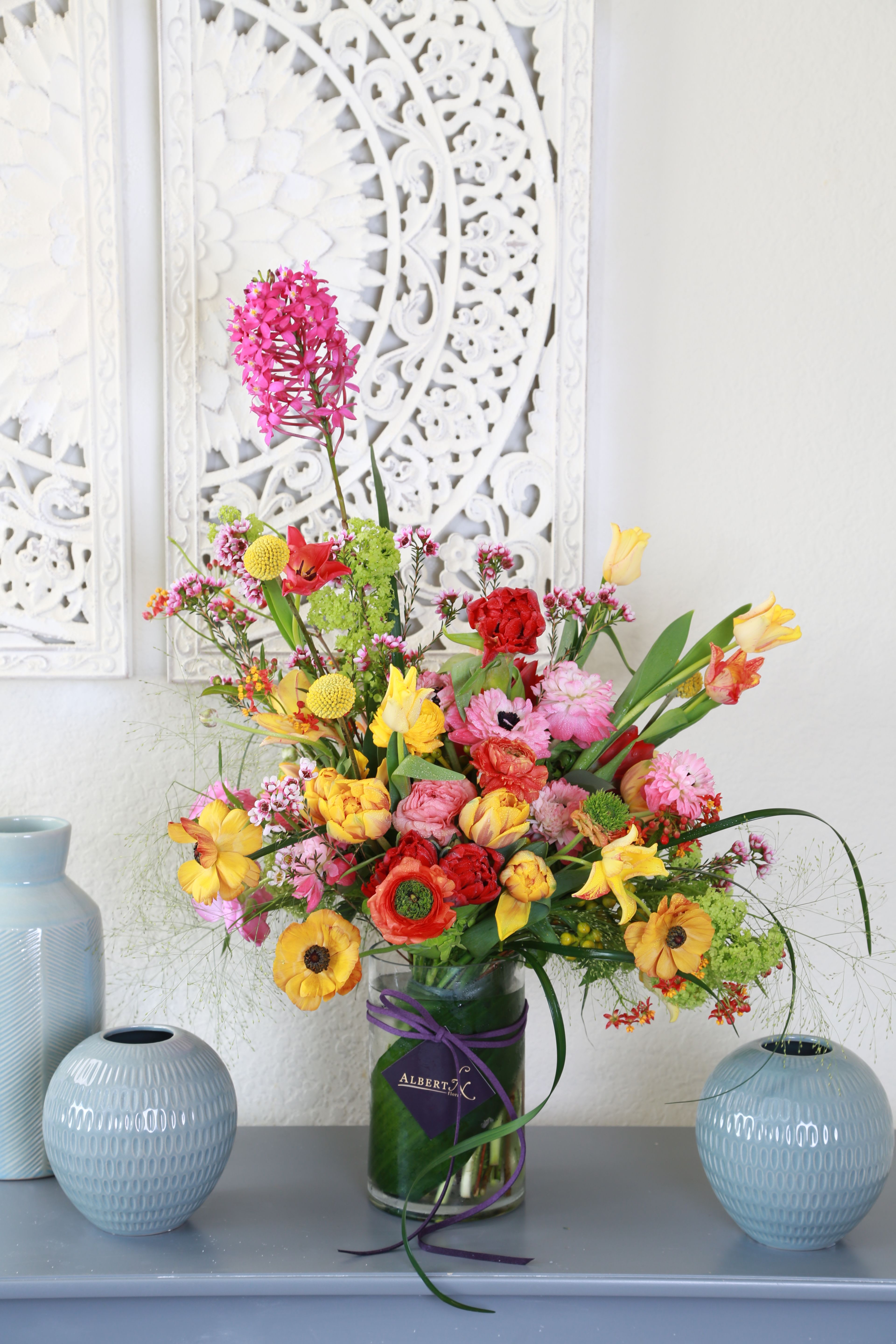 Cheerful love garden - Brighten any room with our signature Spring Bloom arrangement- A vibrant celebration of color and elegance. Expertly arrange with a stunning mix of seasonal blooms, including tulip. ranunculus, roses, anemones and billy balls, this ribbon wrap hand tie bouquet bursts with charm and freshness. Accents of lush greenery and whimsical textures and depth and movement to the design. it is perfect present in clear cylinder vase. this arrangement will deliver with gift box with greeting card.