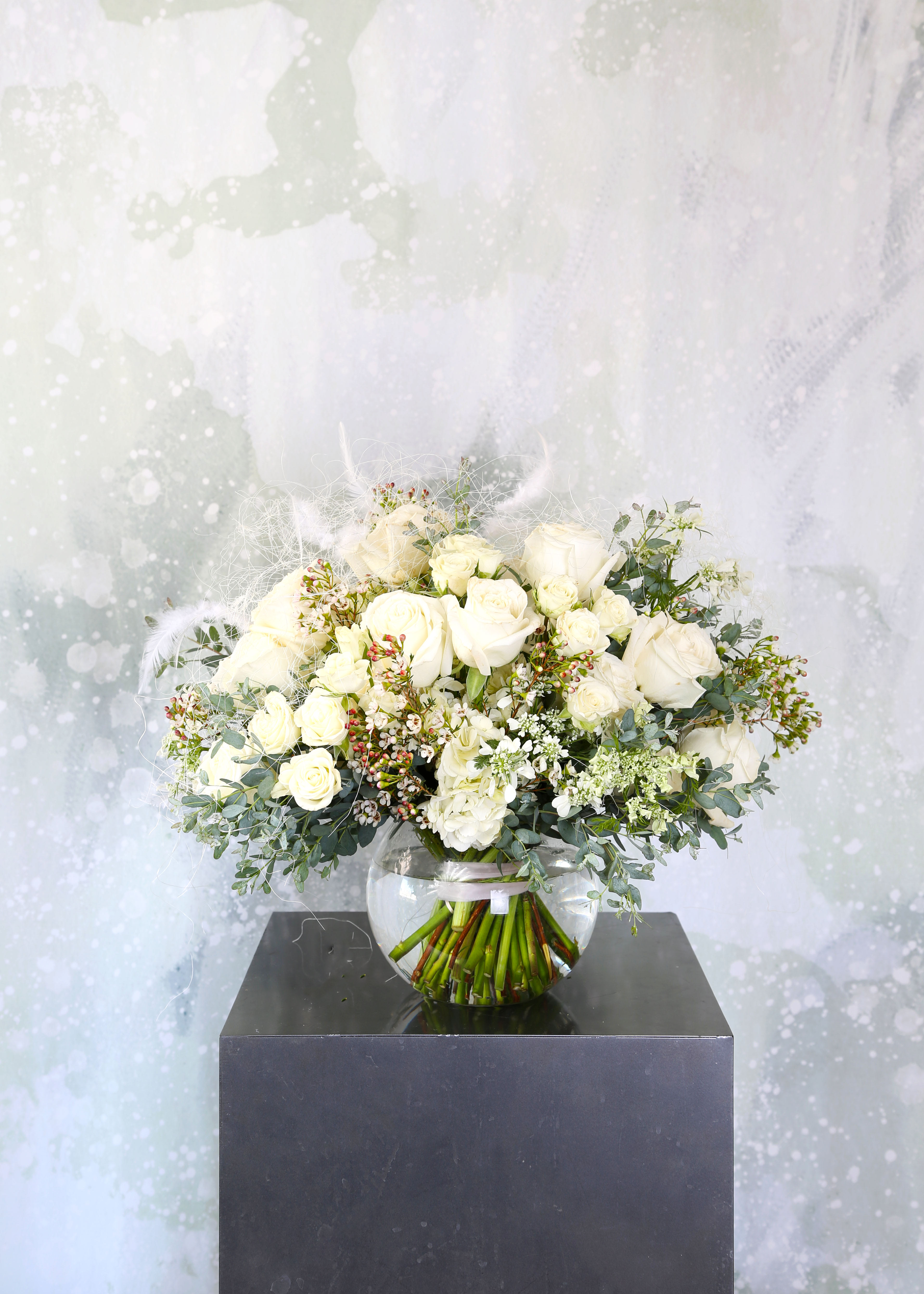 Purity True Love - White Rose represents the beauty and purity of true love.  We called the bridal rose, the unblemished nature of the color white also symbolizes the idea of things that are new and untained. This arrangement arranges in 2 dozen garden roses , spray roses with seasonal green and bloom and finish by our signature Shisaru asa (Natural fiber from Japan) and feather touch in our fan shape silhouette. This arrangement come with 8" round vase. Disclaimer: Photo just represent the overall style, look and feel, which may not be able to identically replicate in some instance. We will only substitute item of equal value or higher value. 