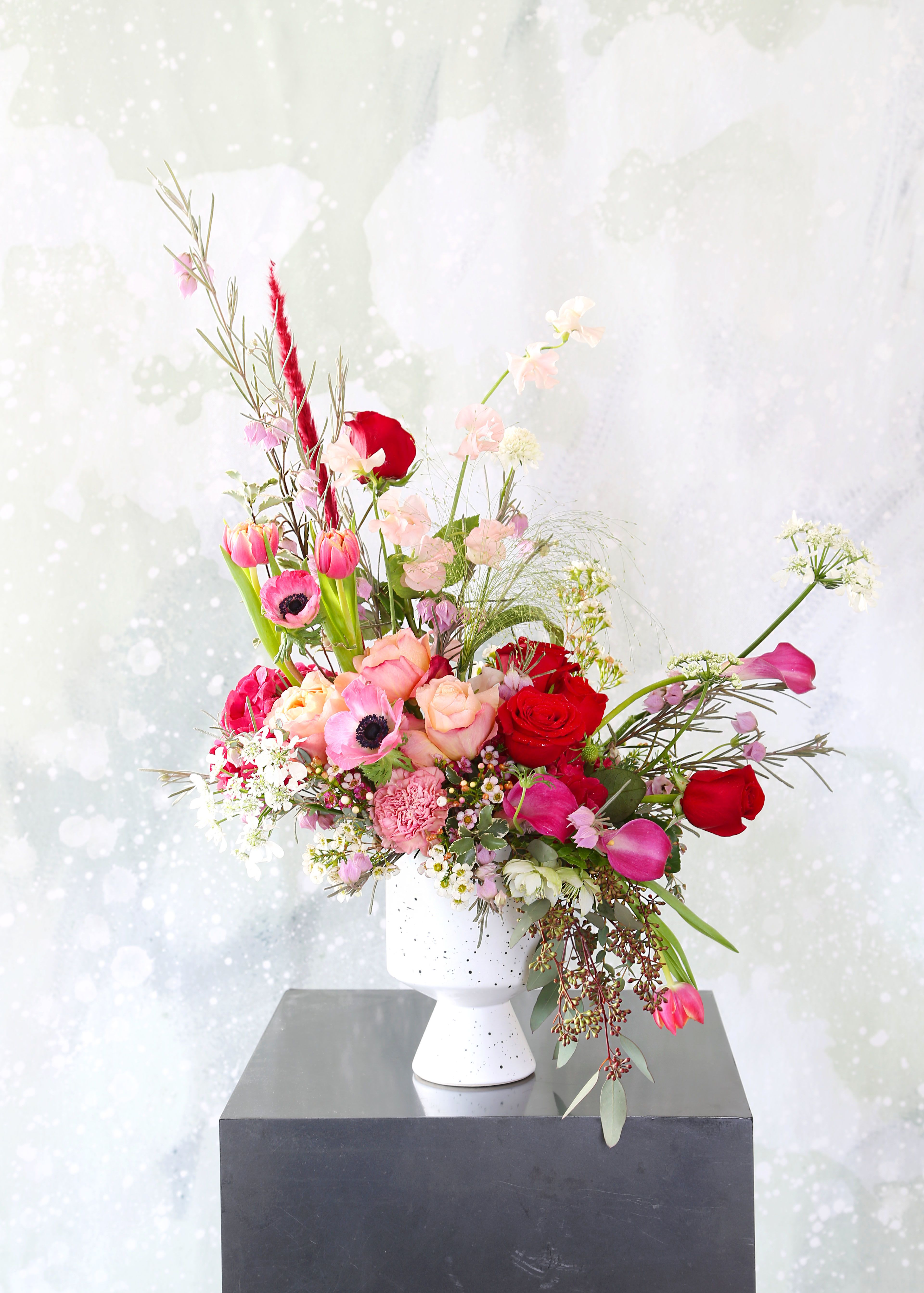 Moulin Rouge - A unique stylish Ombre color arrangement creates on the special Raspberry red hydrangea, Garden rose in color Red and Peach, Calla lilies, Anemone, tulip, sweet pea, Ann Queen Lace, wax flower, carnations with more seasonal bloom and green, it is perfect for the one you love and whoever easy for eyes with lots of textures, lines and variety of depth., It is arranged in a 5" opening ceramic Footed Compote included. It will be delivered with branded gift box and greeting card