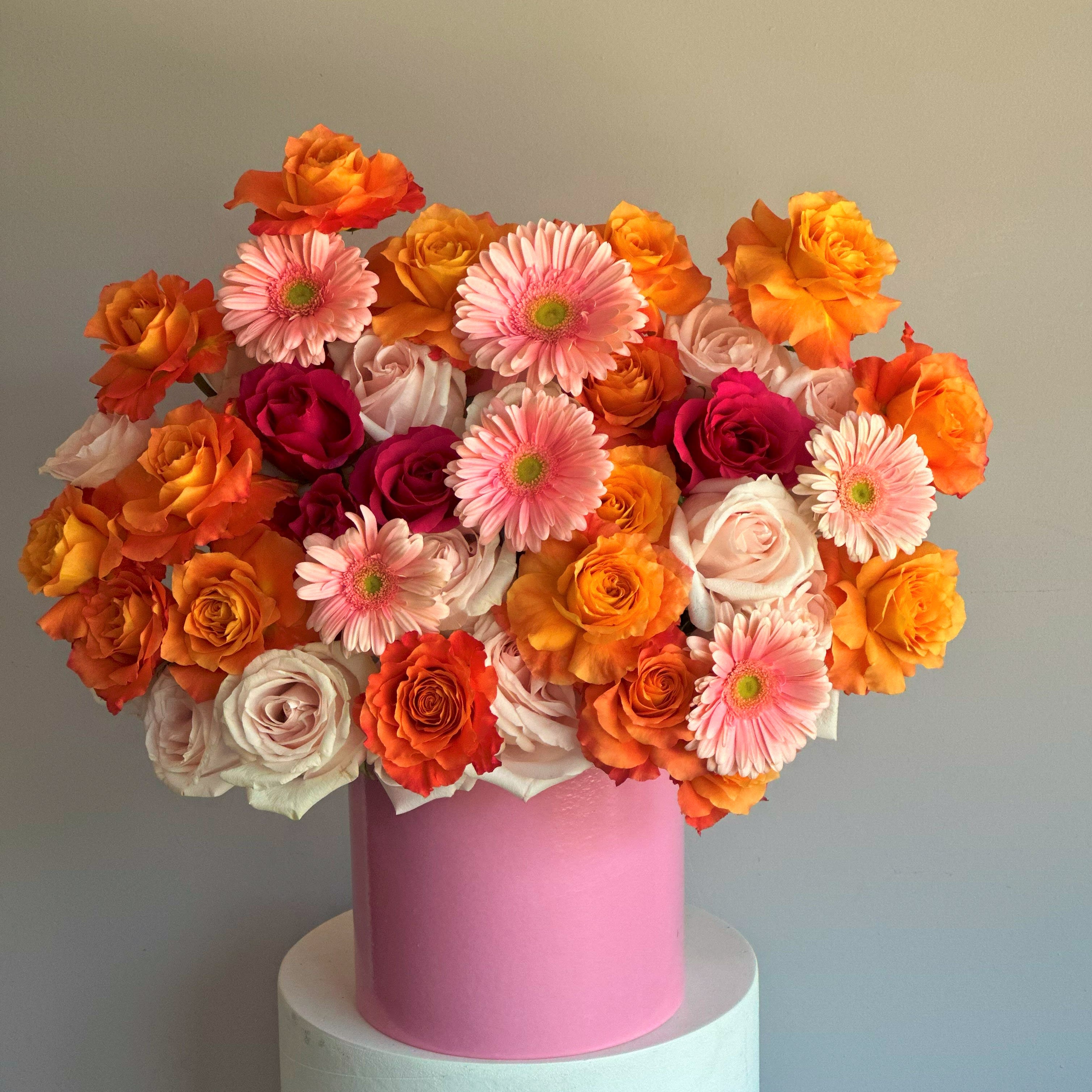 Gabi P - The "Gabi" arrangement is a vibrant and cheerful display that combines an exquisite mix of peach, pink, and red roses with playful pink gerbera daisies. Seasonal flowers can be replaced with similar ones. PREMIUM size is shown in the picture.