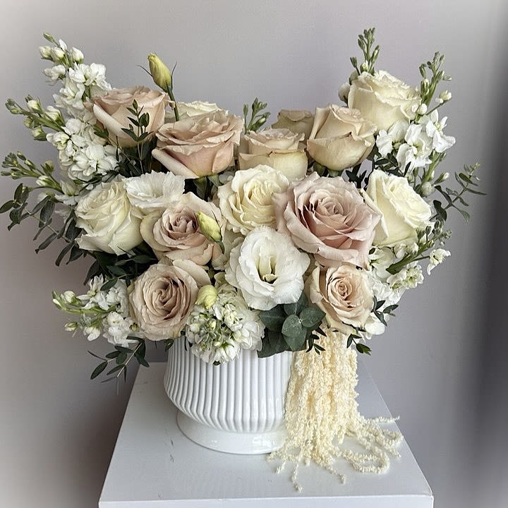 Vibe D - This soft and elegant arrangement features blush pink roses, creamy white blooms, and fresh green accents, artfully arranged in a chic white vase.  Seasonal or unavailable flowers, as well as pots, can be replaced with similar ones.  DELUXE size is shown in the picture.