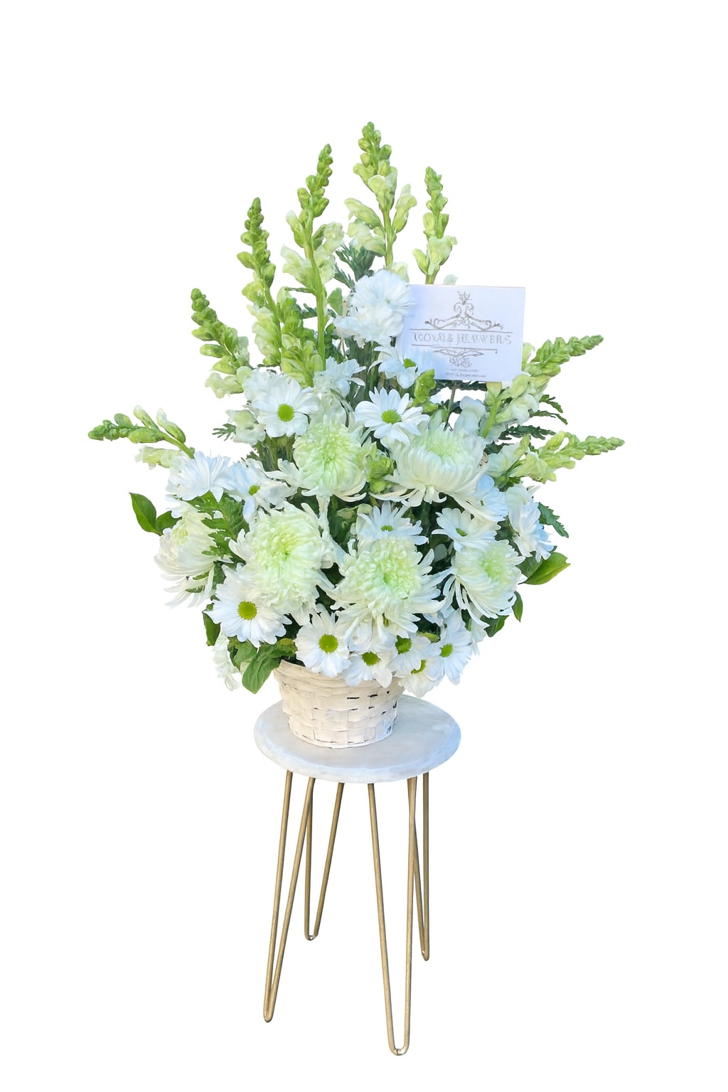 Tall white and green flower basket arrangement with card displayed on a small round stand